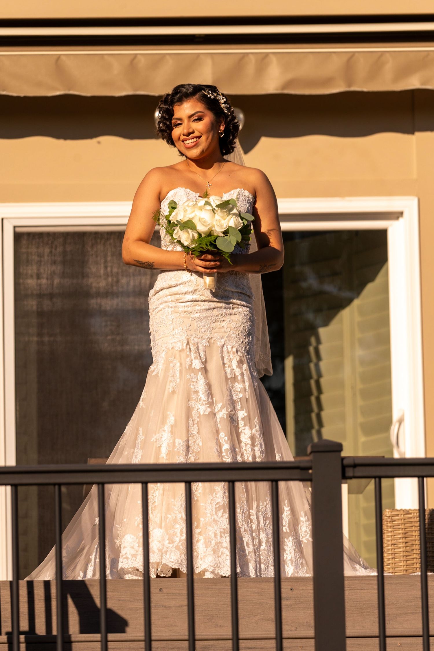White lace wedding dress photographed on a balcony during golden hour.