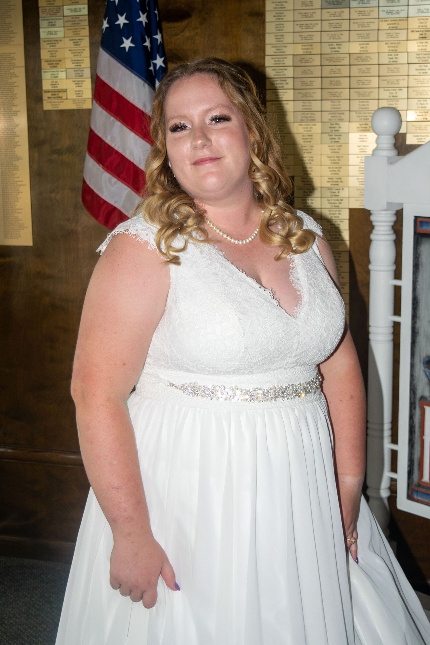Elegant bridal portrait with American flag backdrop showcasing white wedding gown details.