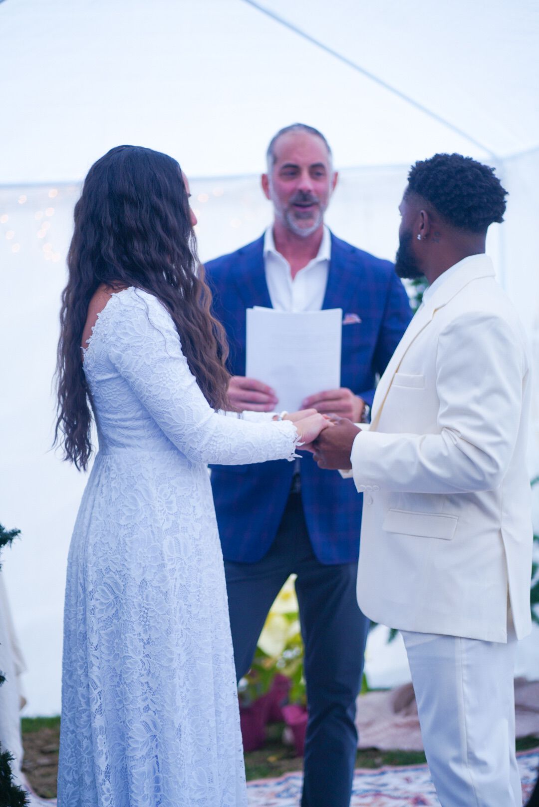 Wedding ceremony in progress with officiant and couple exchanging vows outdoors.