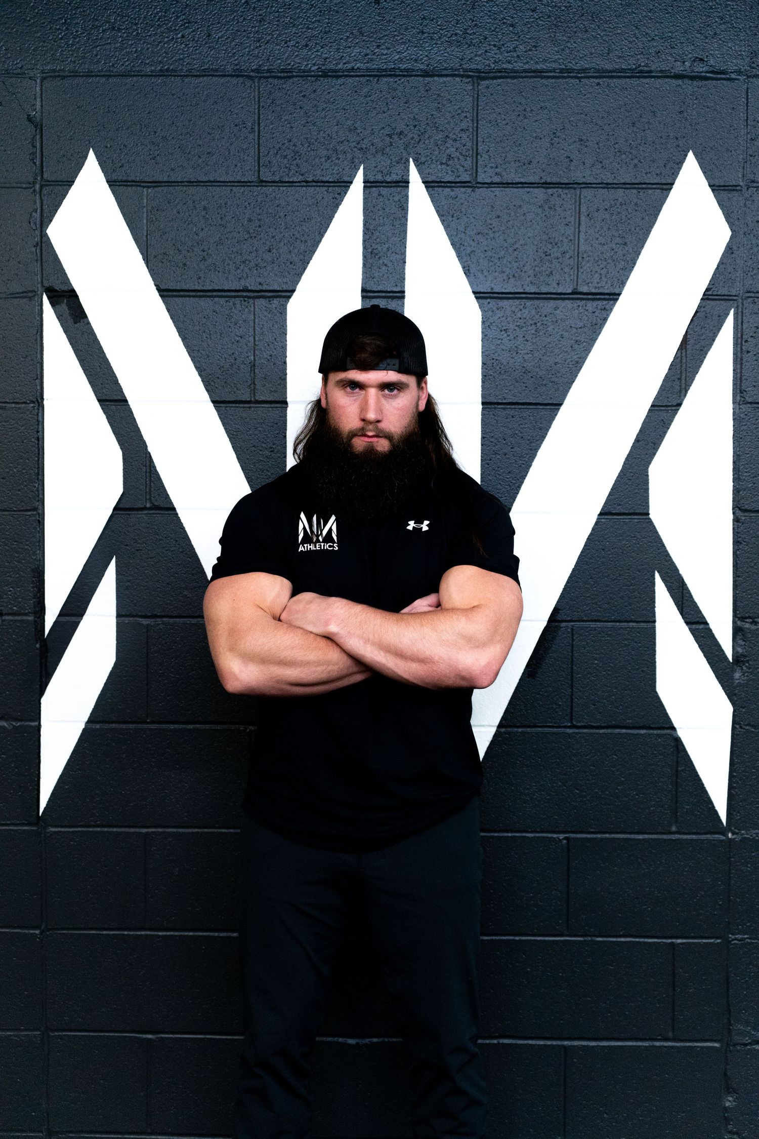Person in black clothing standing against geometric black and white wall art.