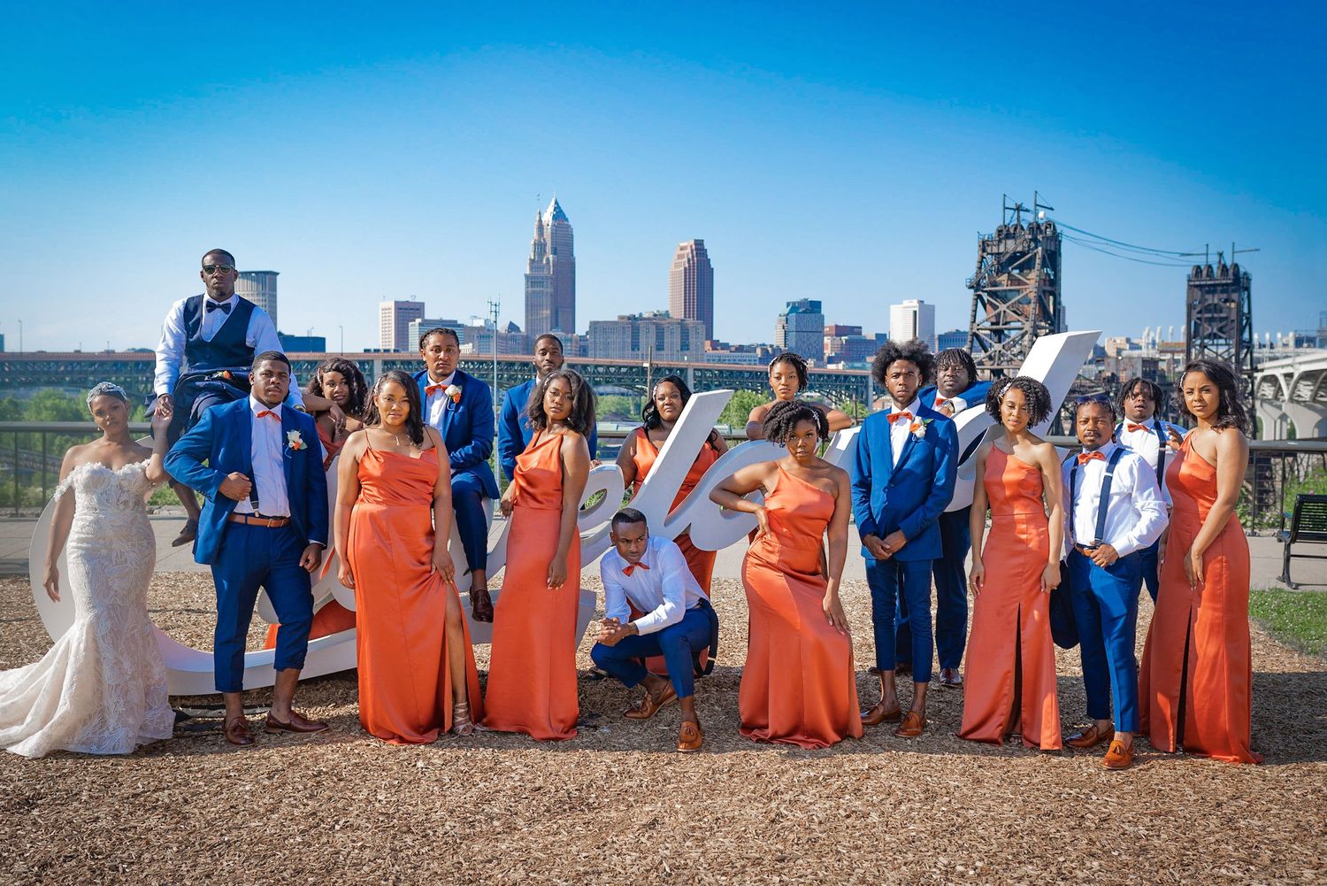 Wedding party in blue and coral attire poses against urban backdrop.