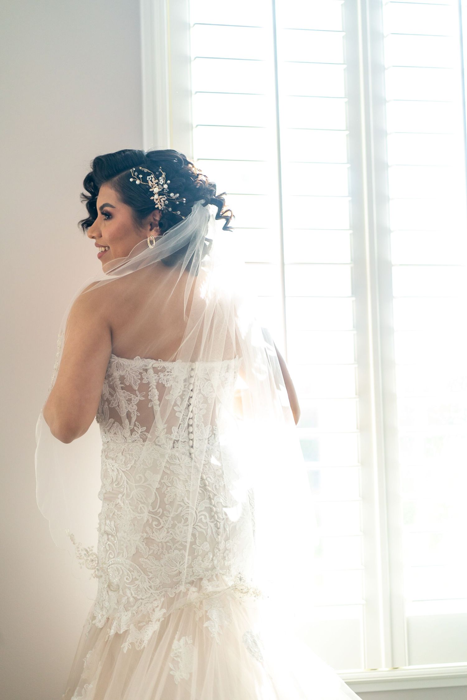 Ethereal bridal portraits with delicate lace details and flowing veil near sunlit windows.