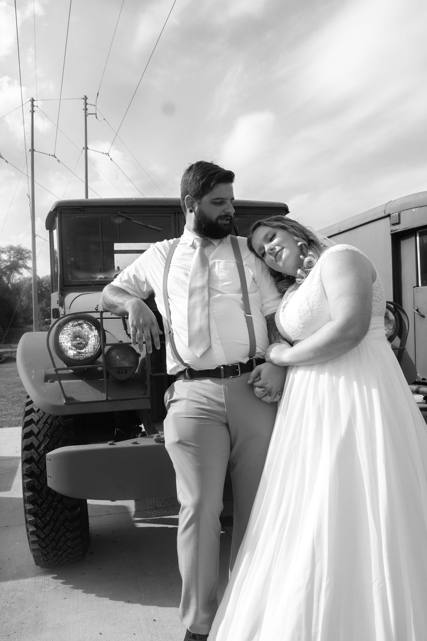 Wedding couple poses together near a vintage truck in black and white photography.