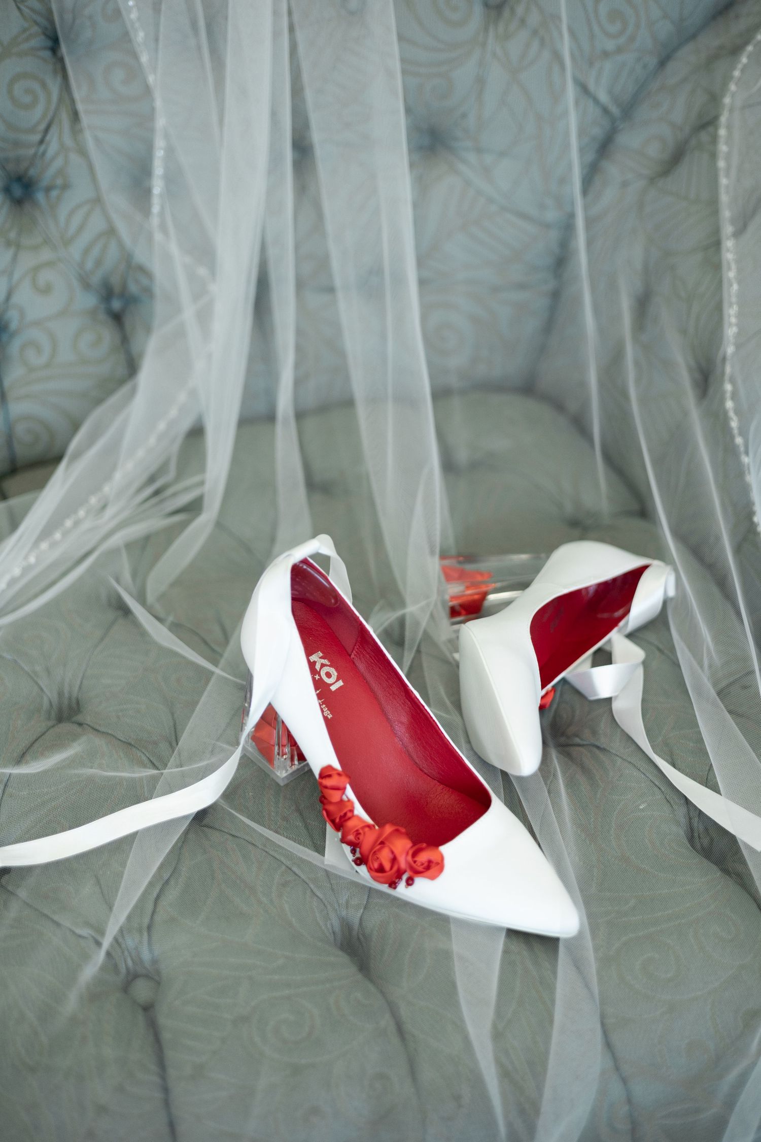 Red and white high heel shoes against a white sheer fabric background.
