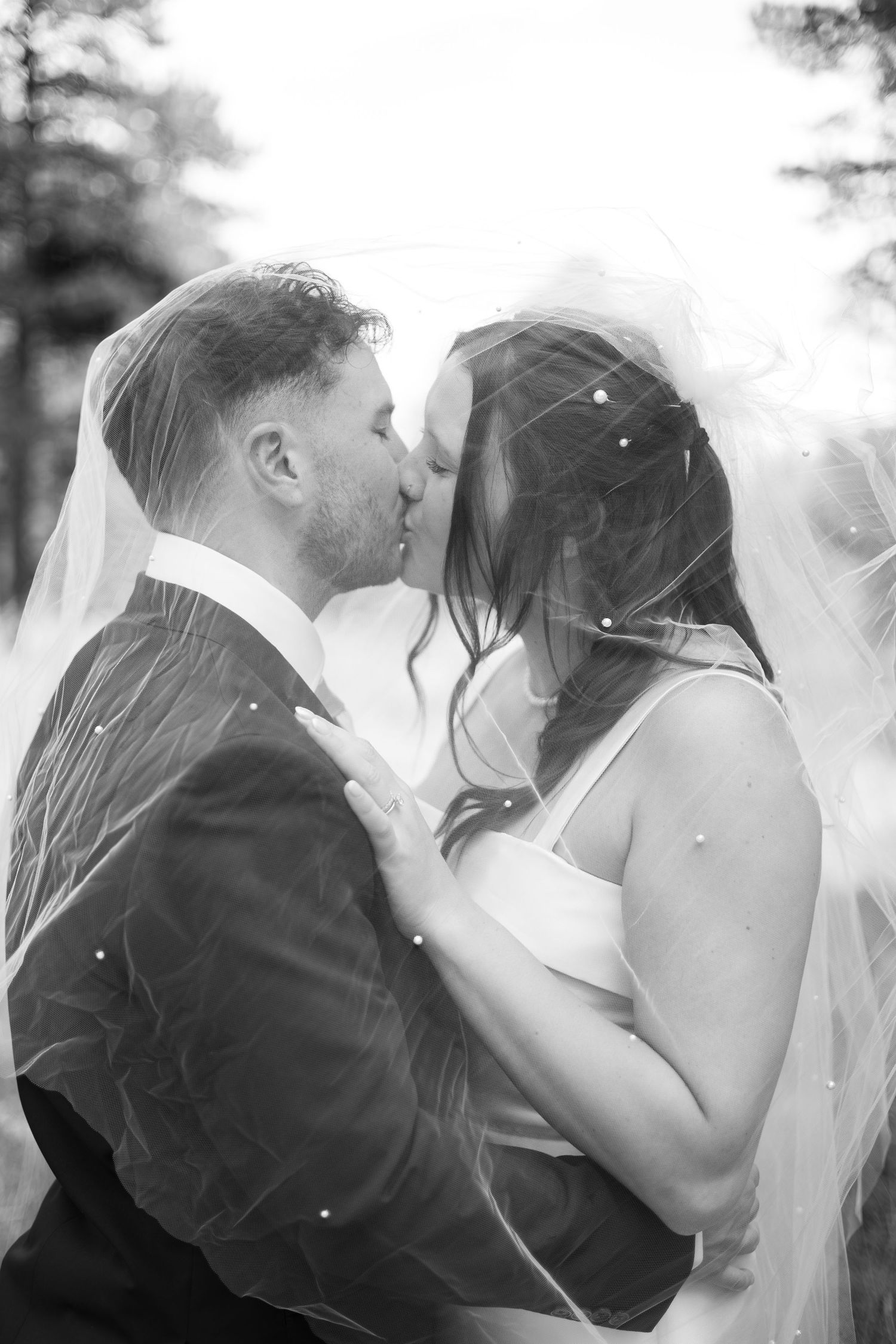 A romantic wedding sequence showing a couple kissing through a veil in black and white photography.