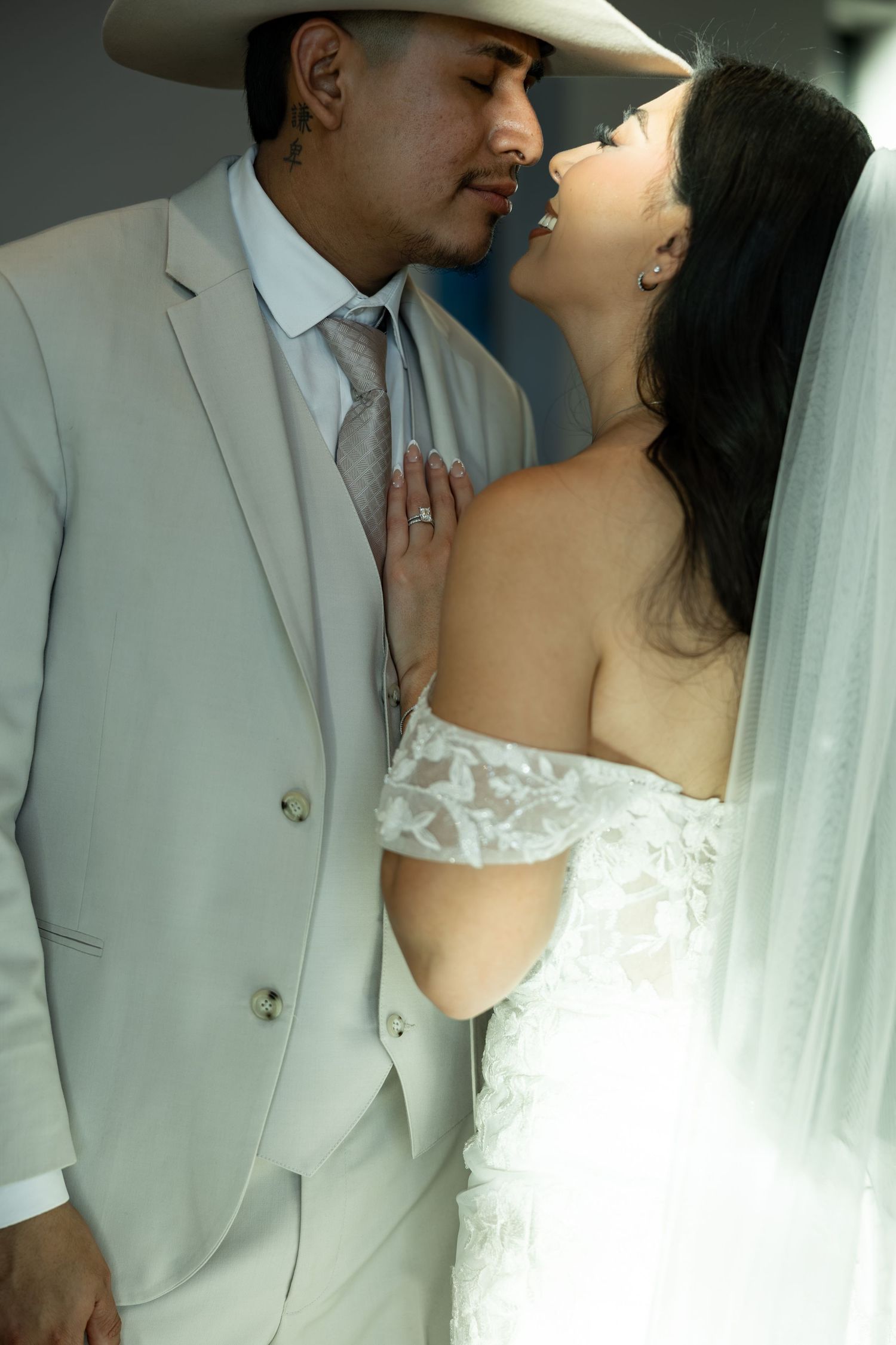 A romantic close-up of newlyweds in white formal wear sharing an intimate moment.