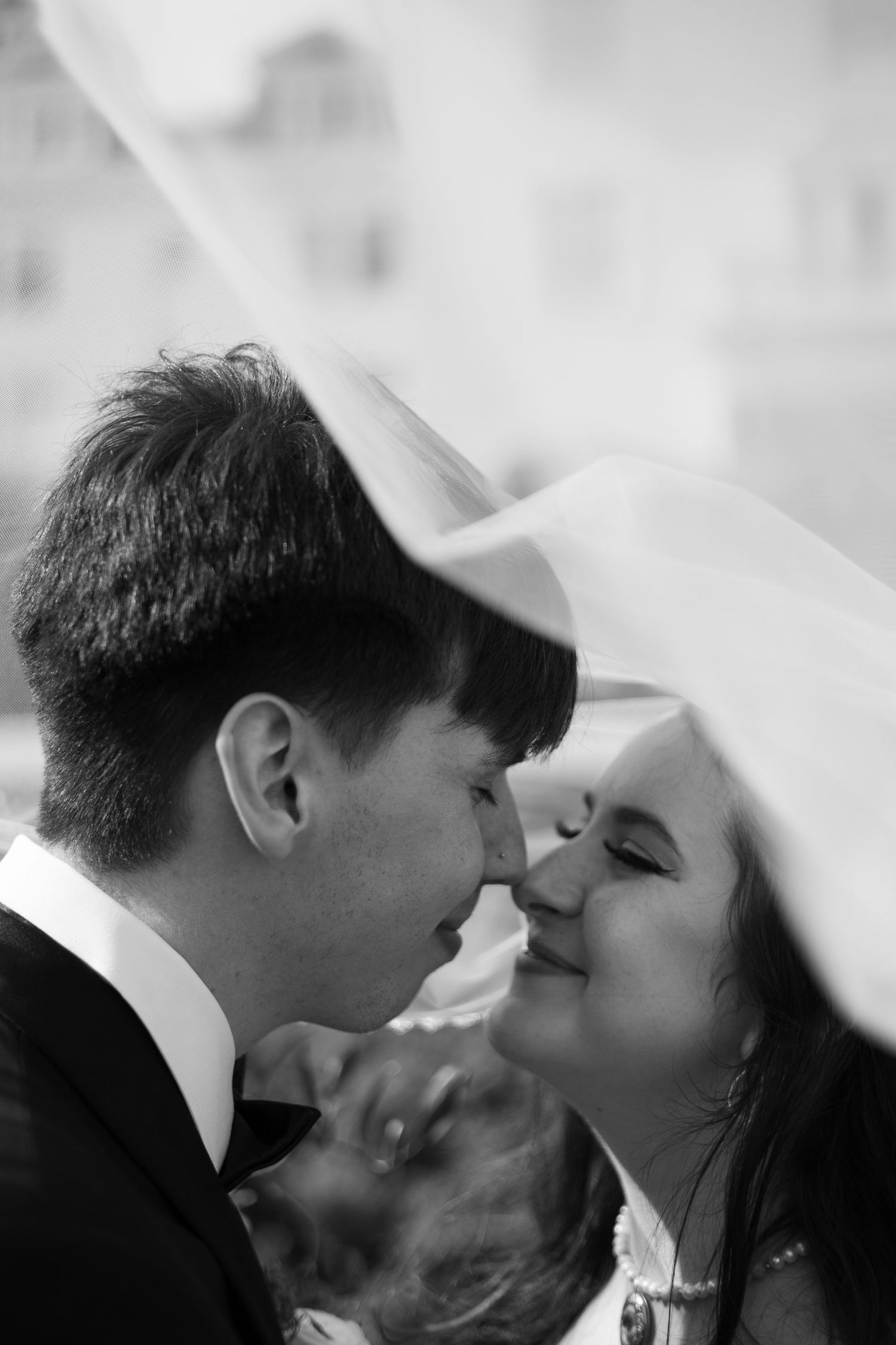 A romantic black and white photograph capturing a tender kiss shared under a veil.