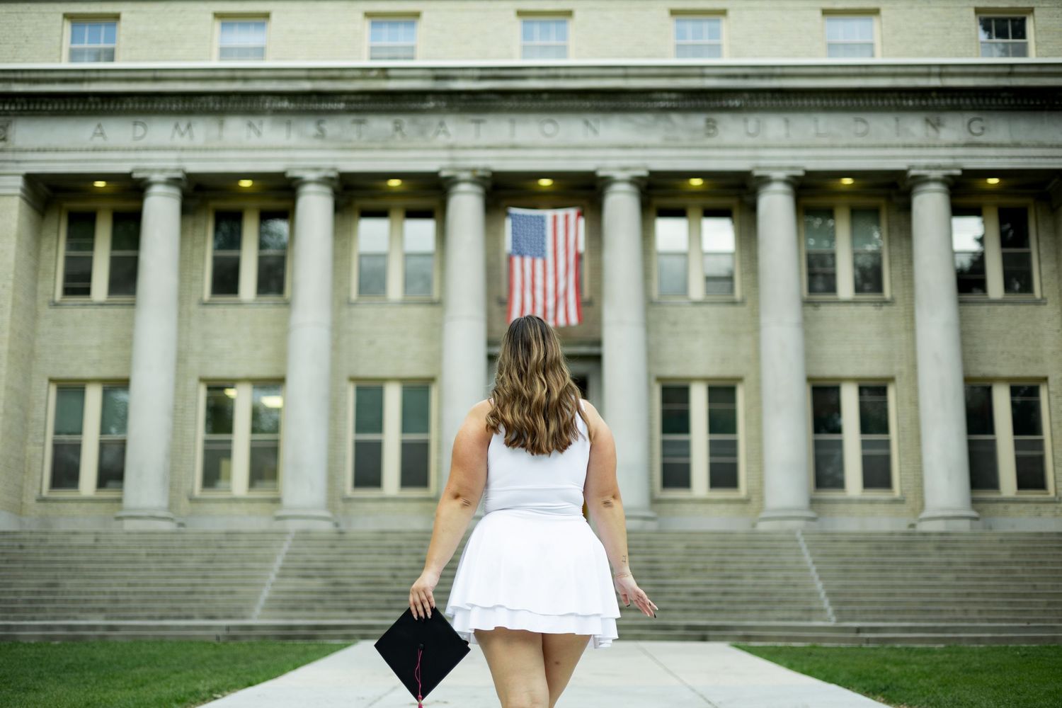 A uniform row of windows spans across a classic stone building facade with an American flag displayed.