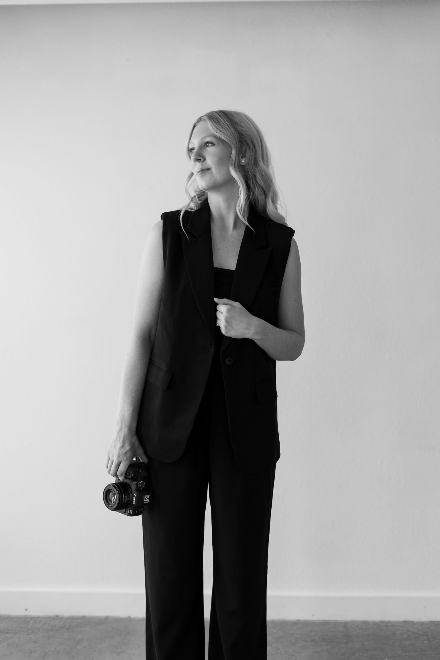 Black and white fashion editorial series showing model in sleek black pantsuit against minimalist backdrop.
