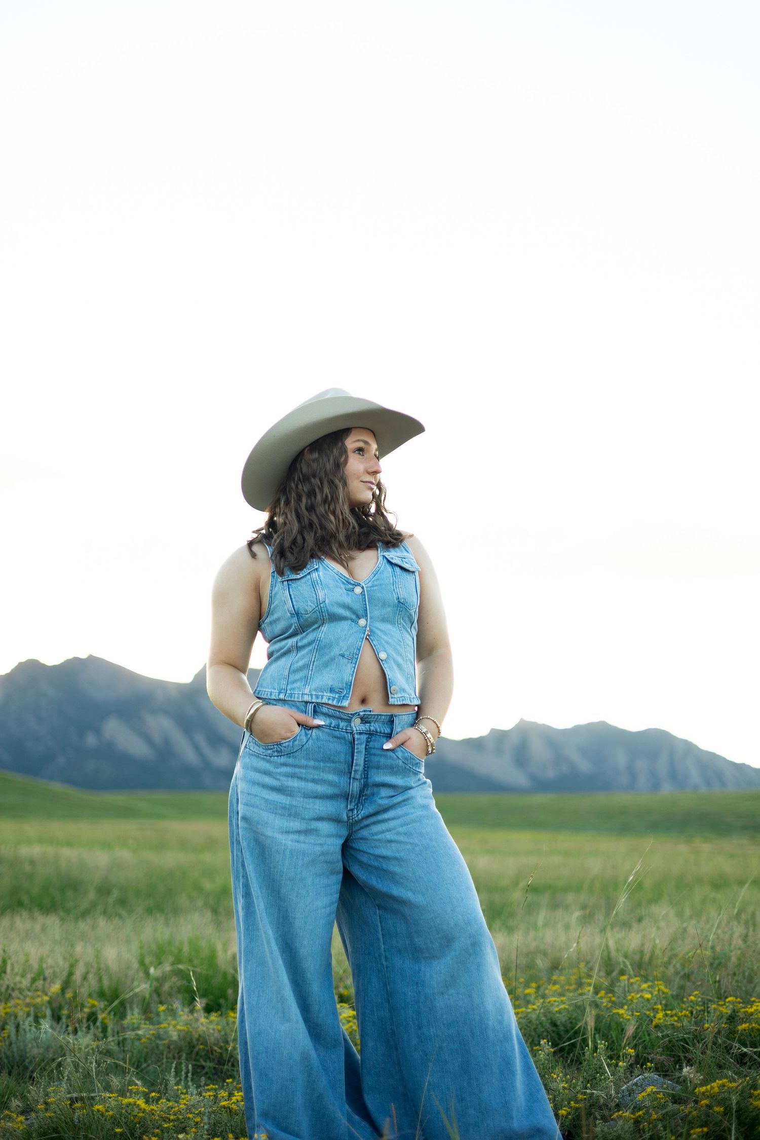 Denim overalls against mountain landscape with wildflowers in scenic meadow under open sky.