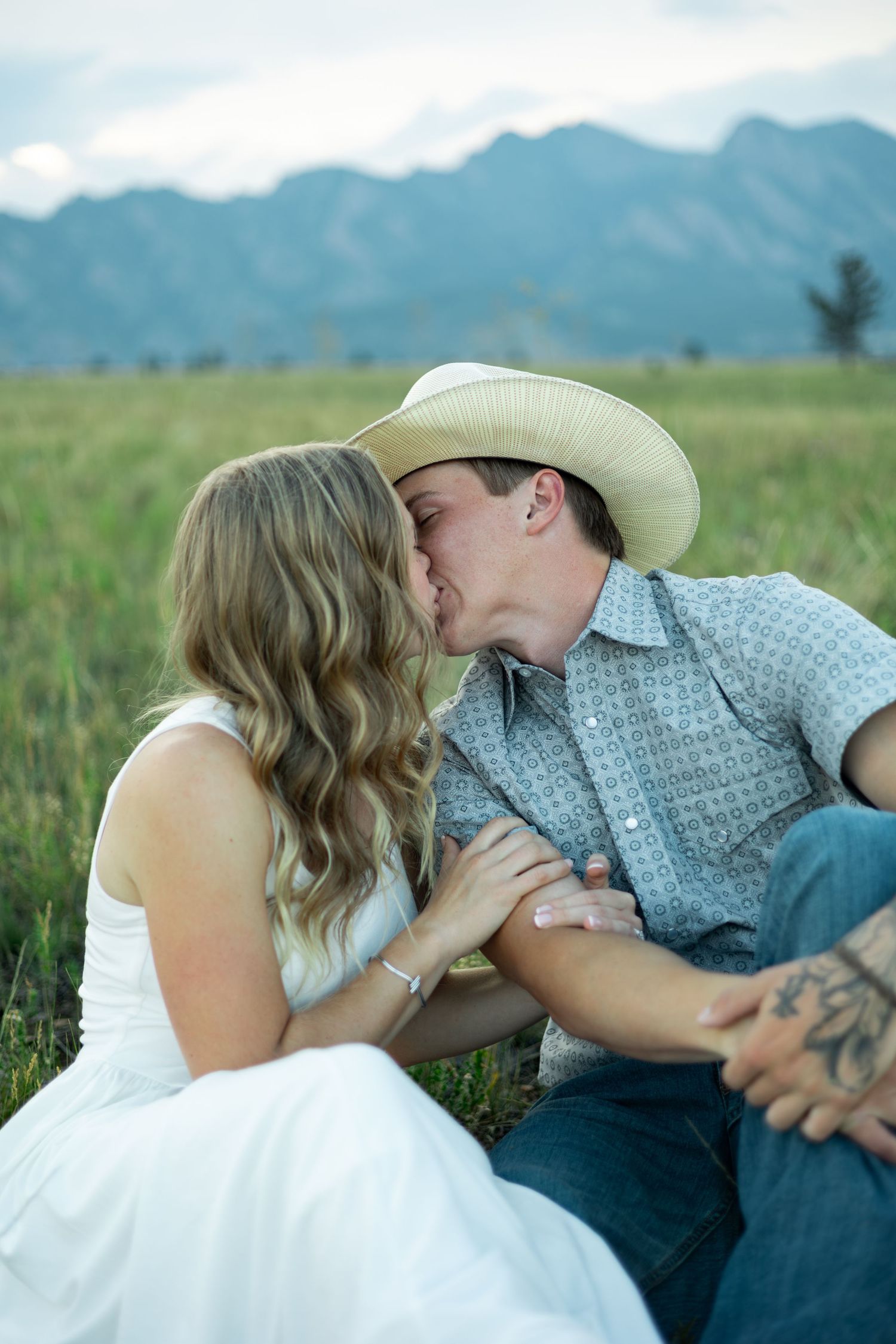 A romantic moment between a cowboy and his bride in a scenic mountain meadow.