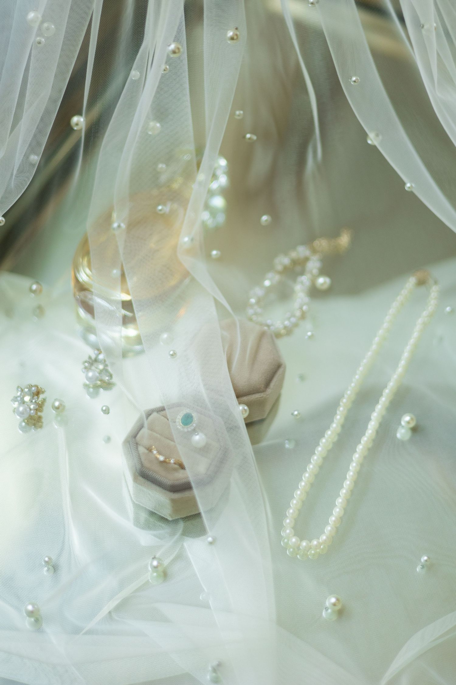 Delicate detail of wedding veil with pearl embellishments and soft fabric texture.