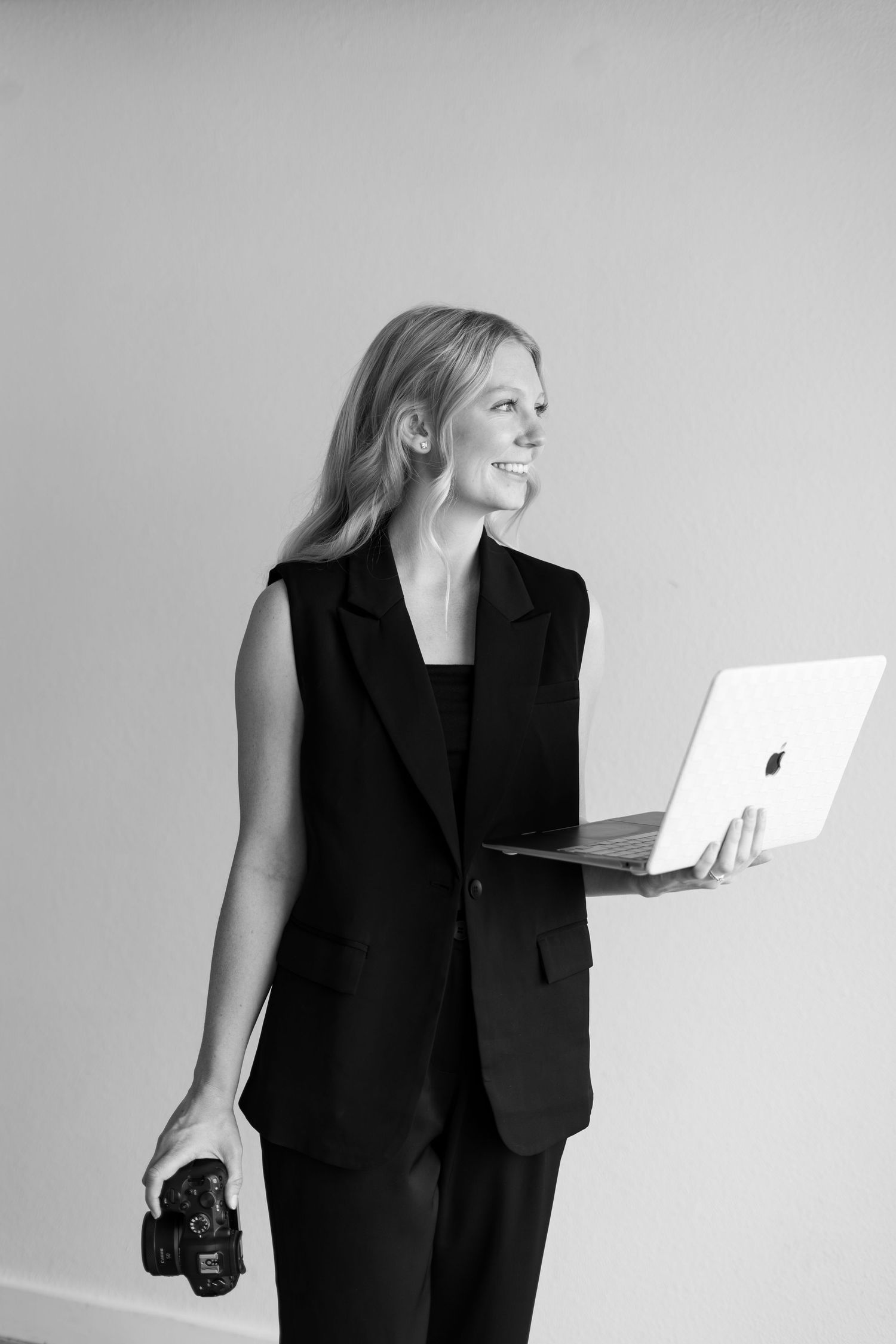 Professional wearing black business attire holds papers while interacting with documents on white background.