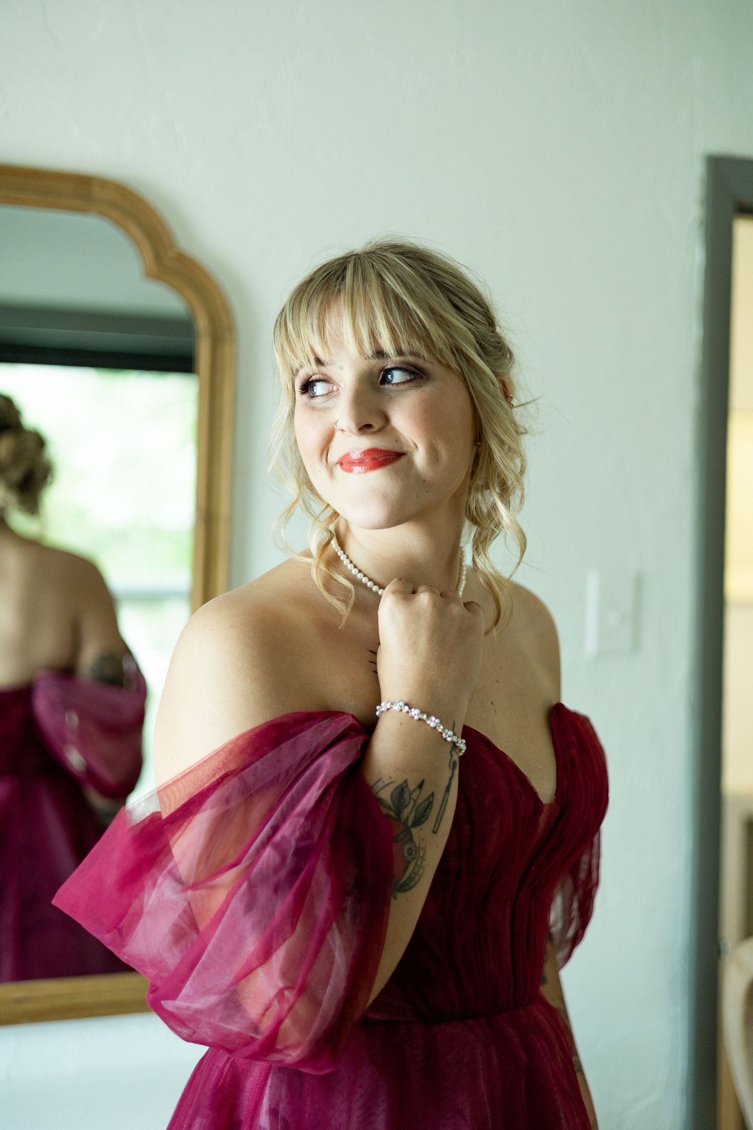 Side view of someone wearing an elegant burgundy off-shoulder gown with tulle sleeves.