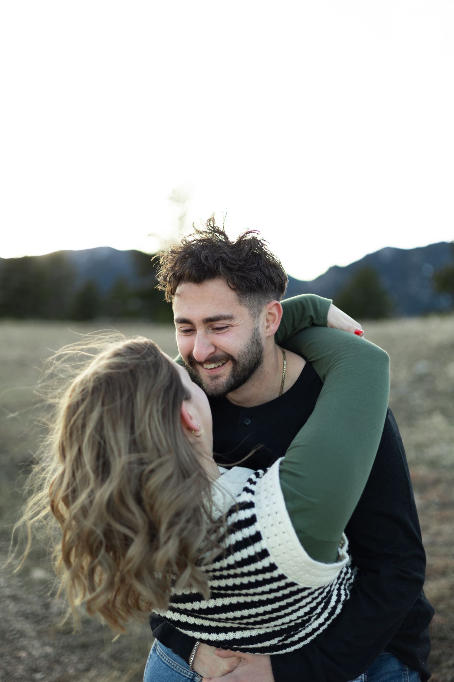 A tender embrace captured during sunset with mountains in the backdrop.