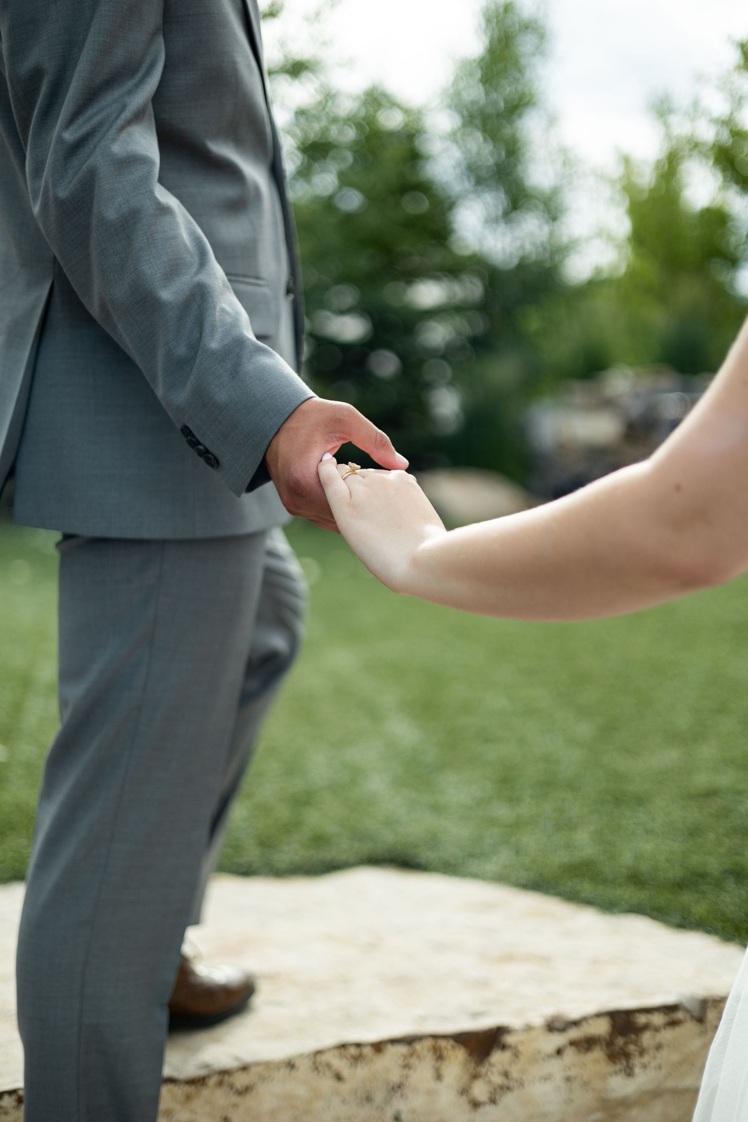 A close-up shot of hands holding during an outdoor wedding ceremony.