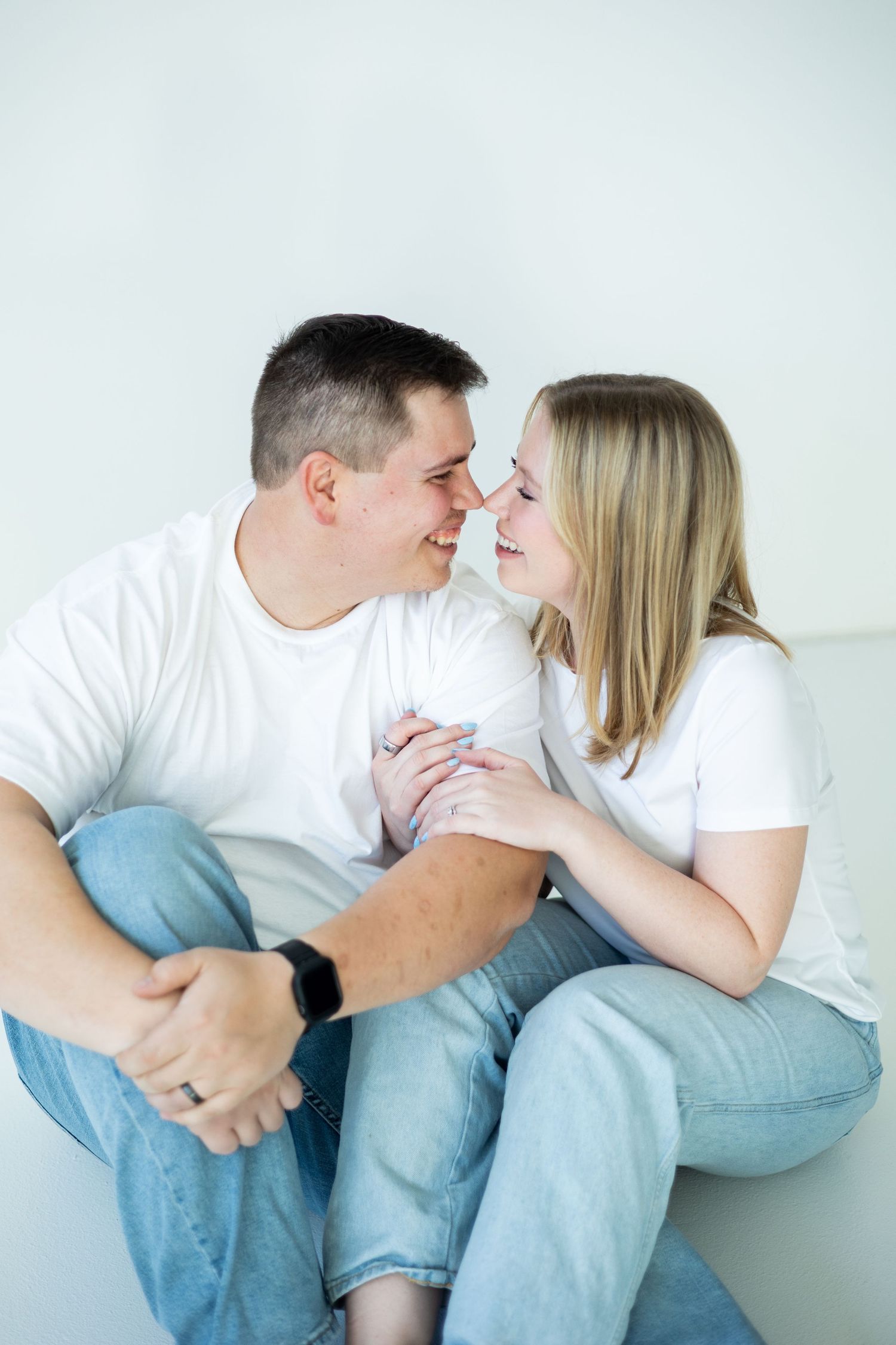 Happy couple wearing matching white t-shirts and jeans sharing an intimate moment together.