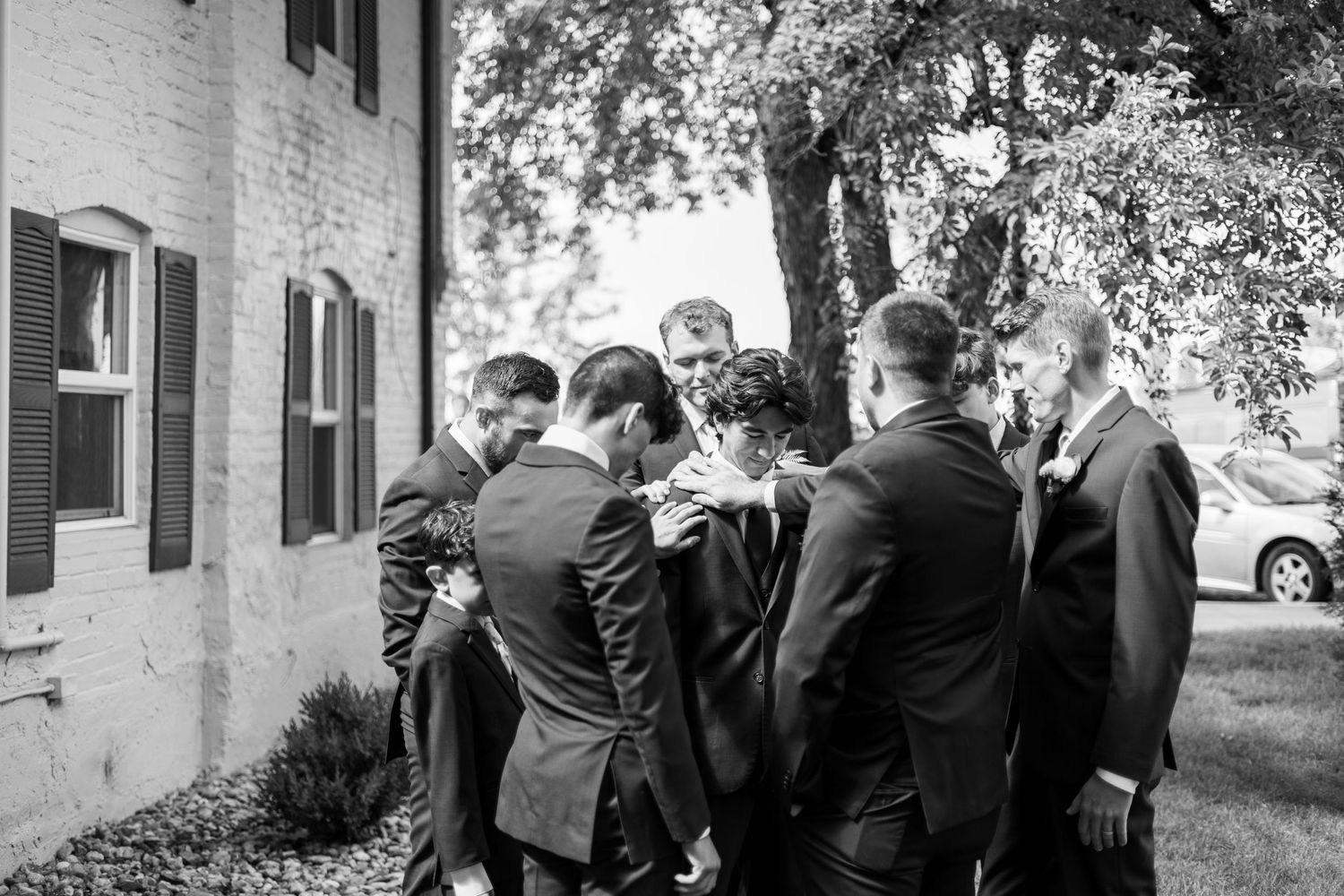 Black and white photo of groomsmen huddled together outdoors.