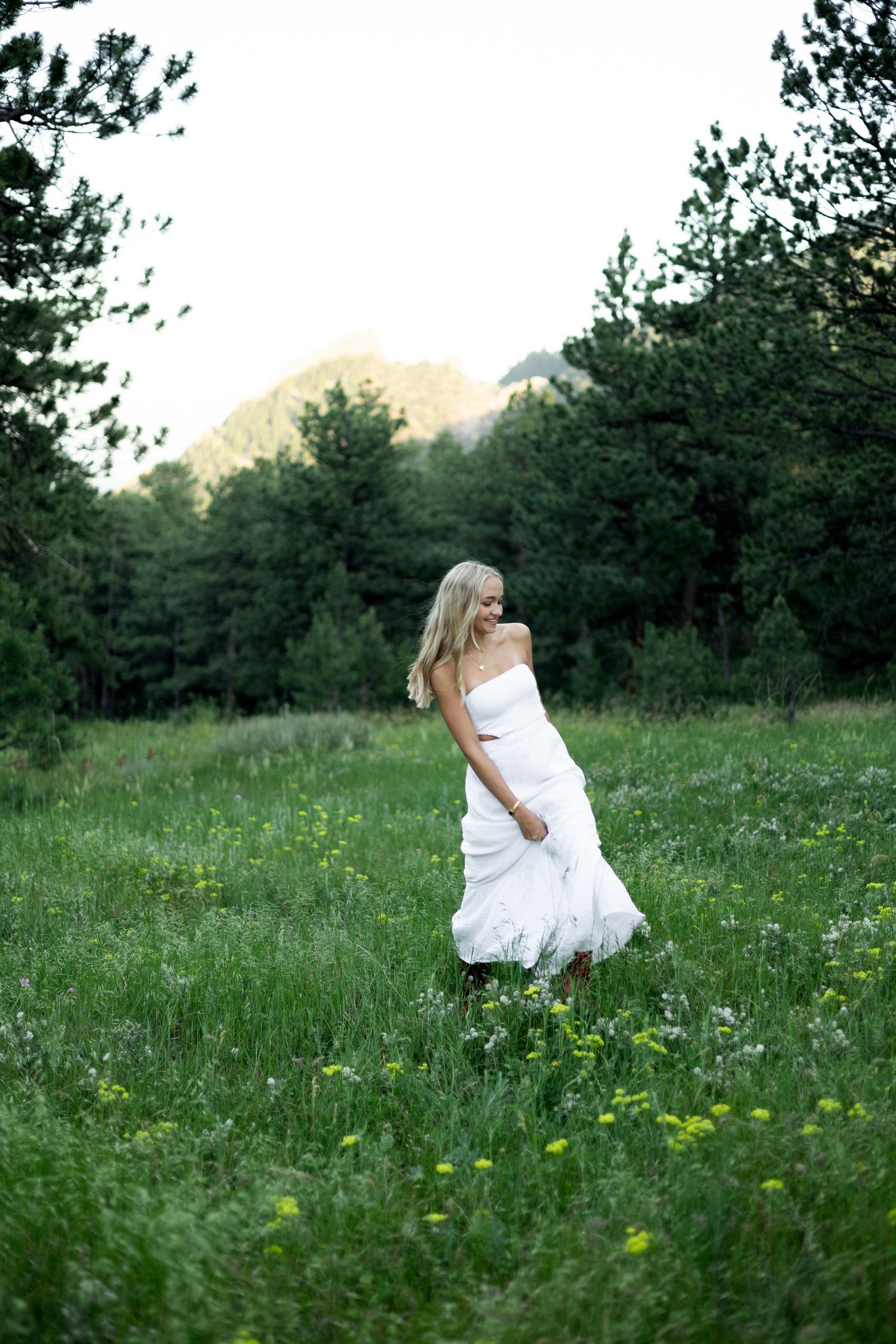 Romantic outdoor photography sequence featuring a white dress contrasting with lush green meadow and forest backdrop.