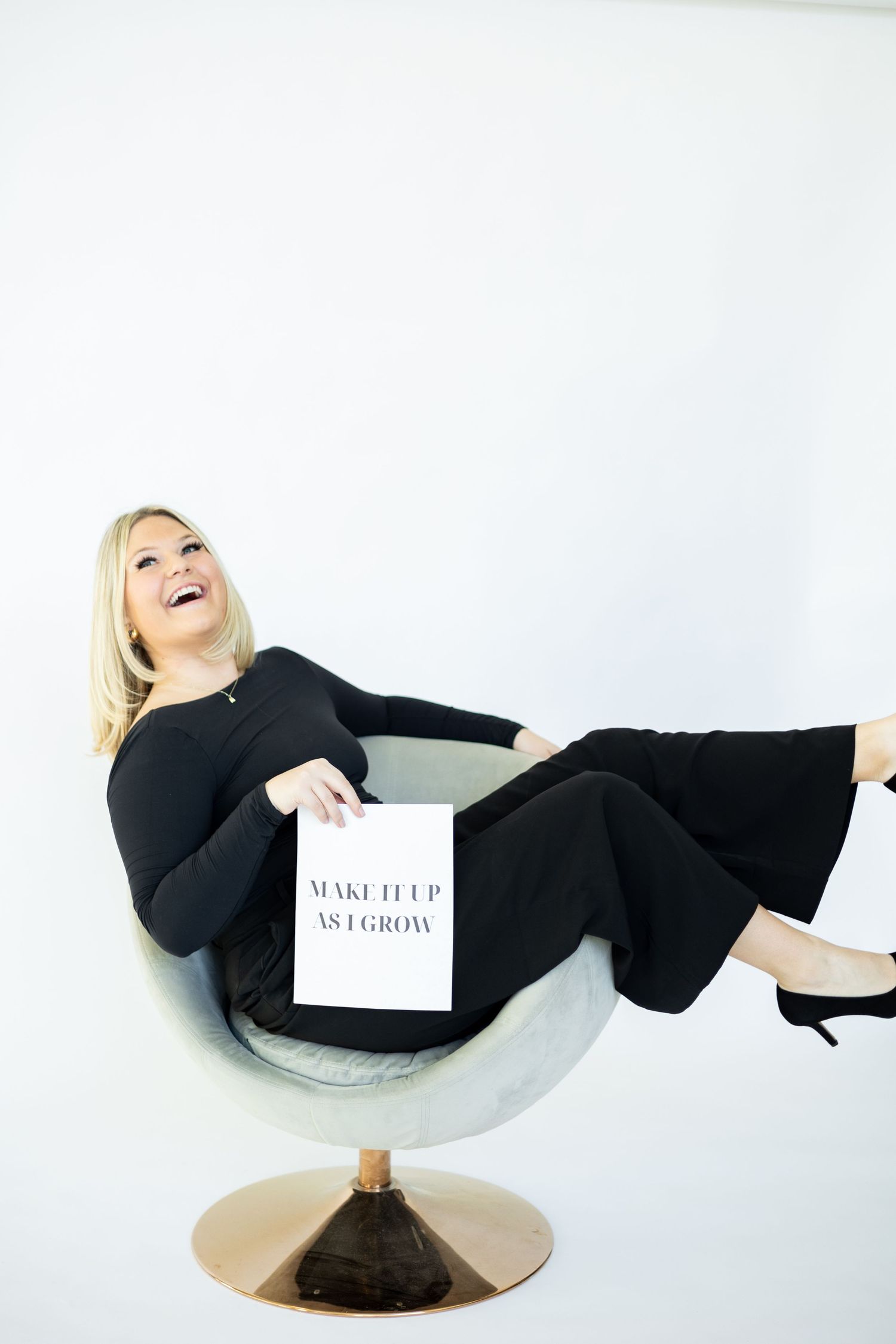 Person lounging in modern chair with marketing materials and joyful expression.