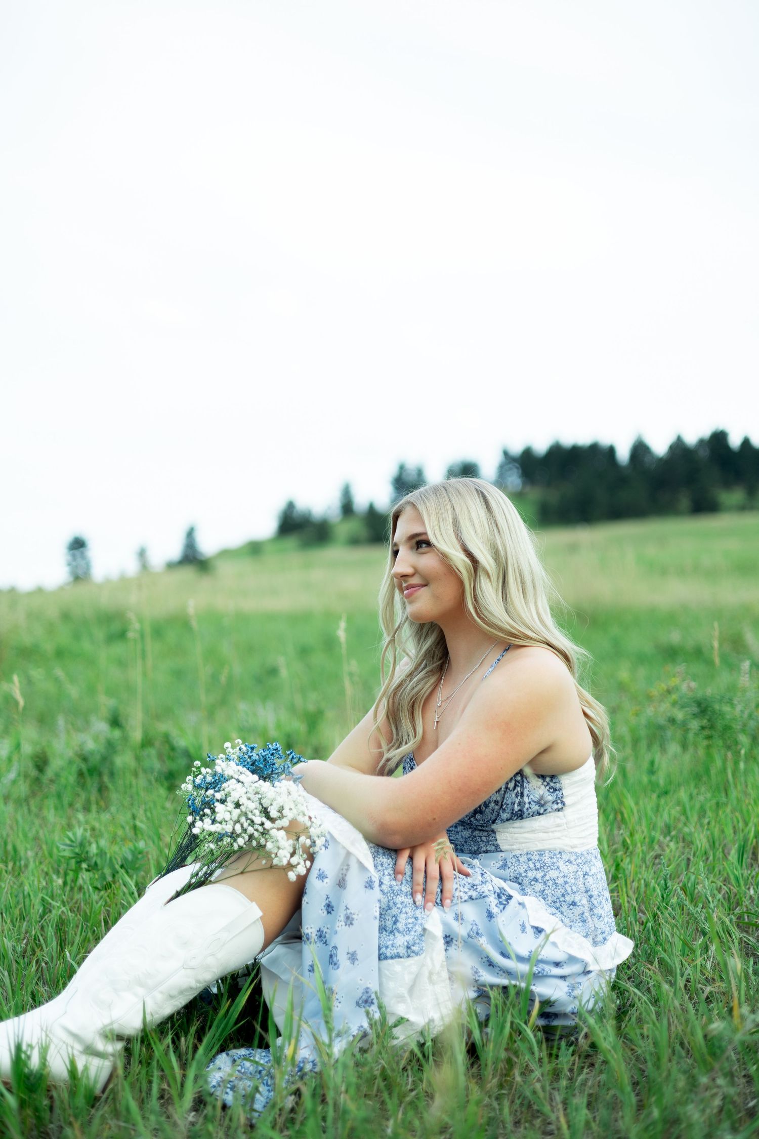 Someone with blonde hair wearing a floral dress relaxes in a grassy meadow on a sunny summer day.