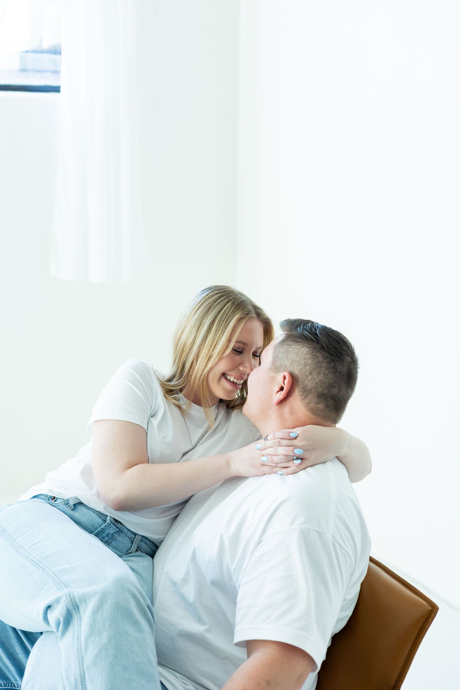 Intimate couple in matching white t-shirts share a tender moment while sitting together indoors.