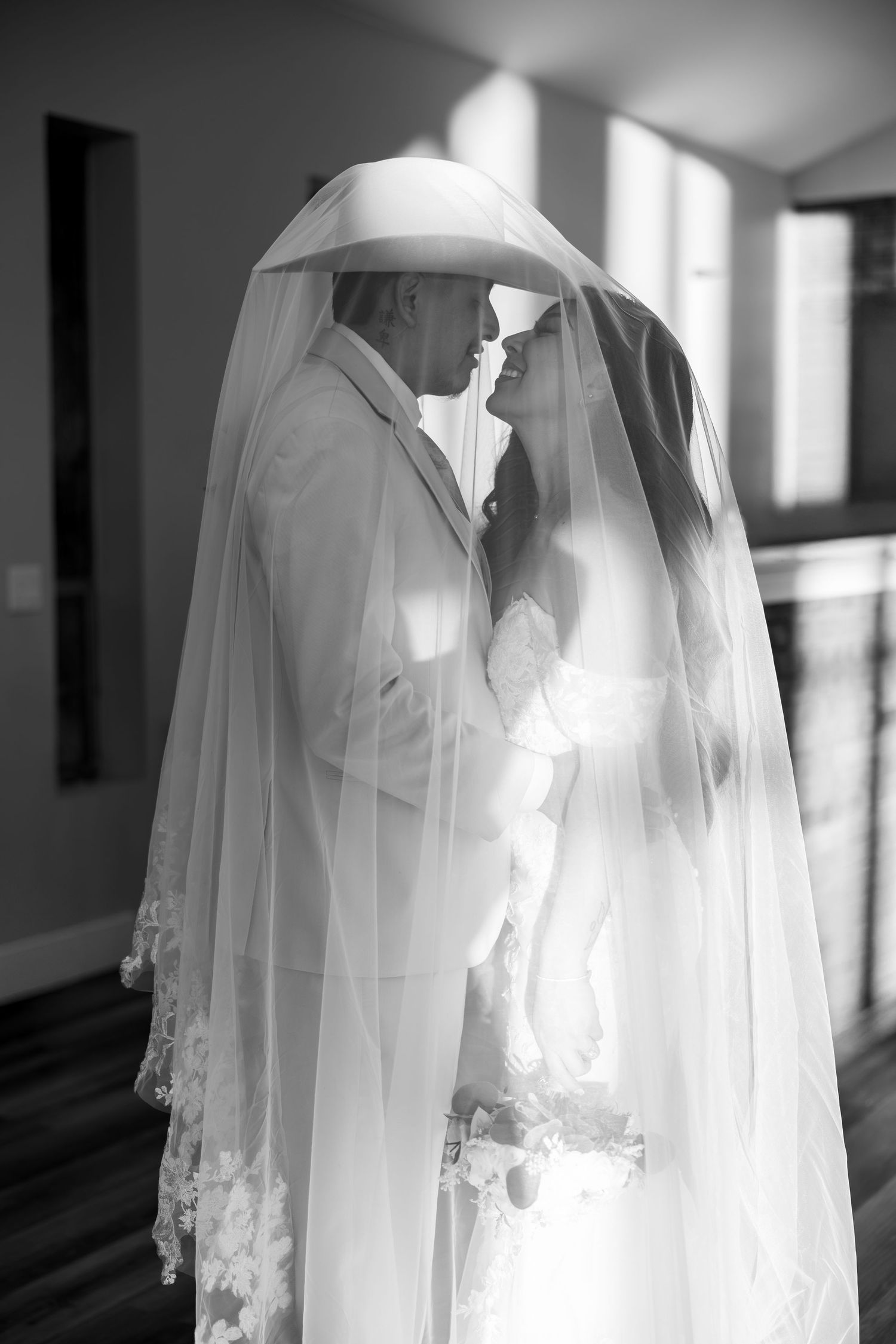 An ethereal bridal veil floating in natural window light creating a dramatic silhouette.