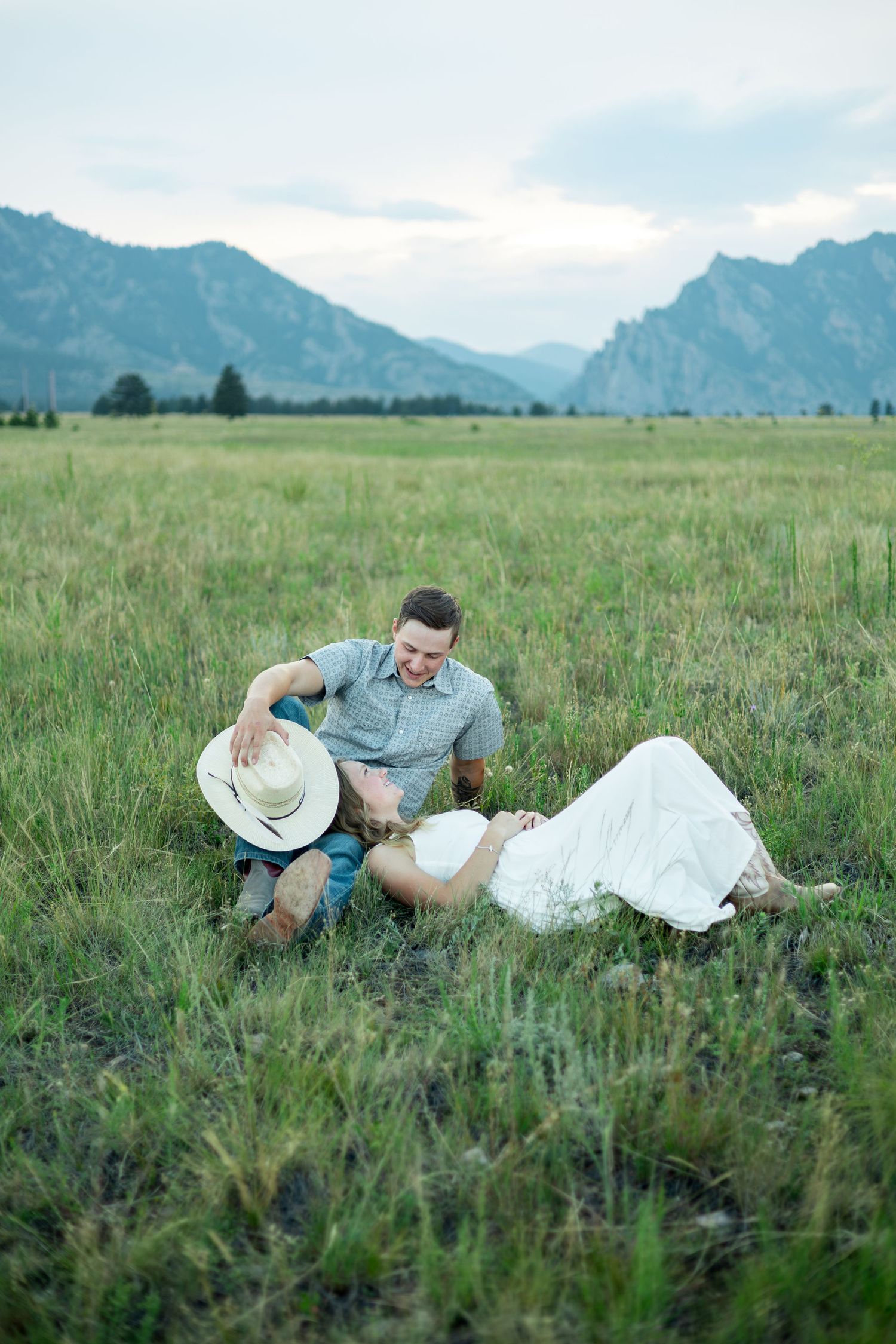 Couple lying in a green mountain meadow surrounded by stunning mountain views on a romantic outdoor date.