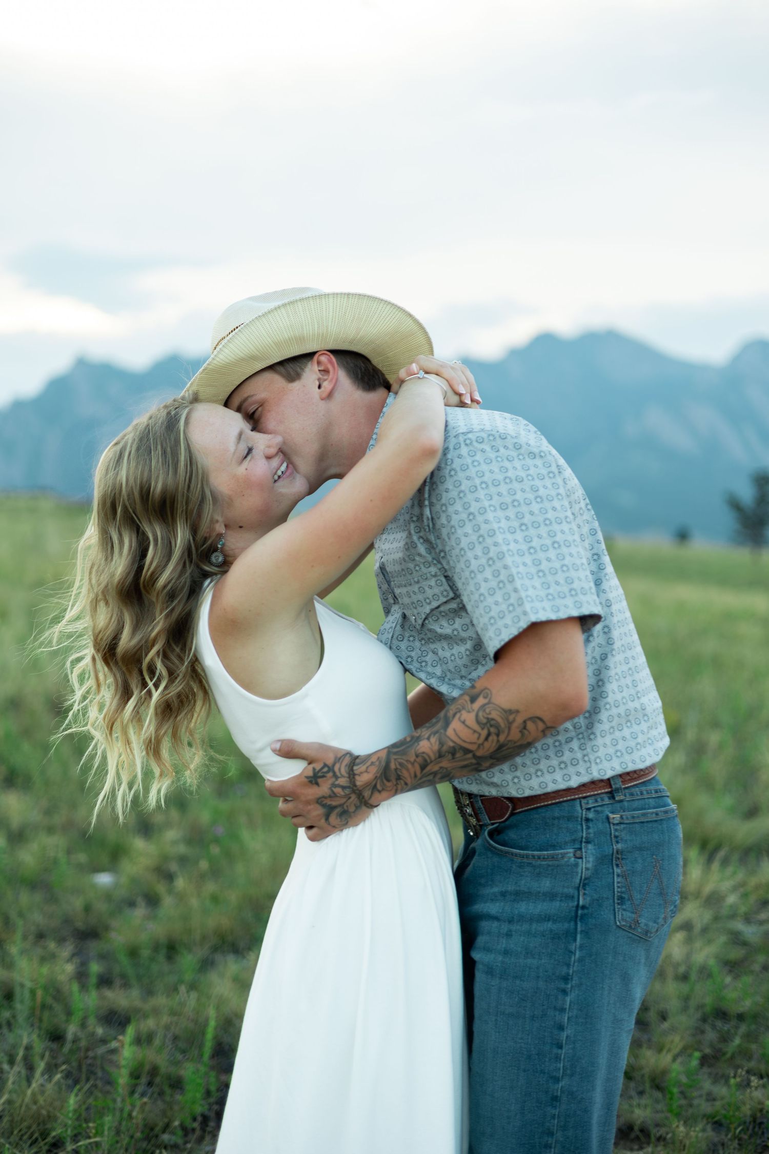 A loving couple share a romantic moment together in front of a scenic mountain landscape.