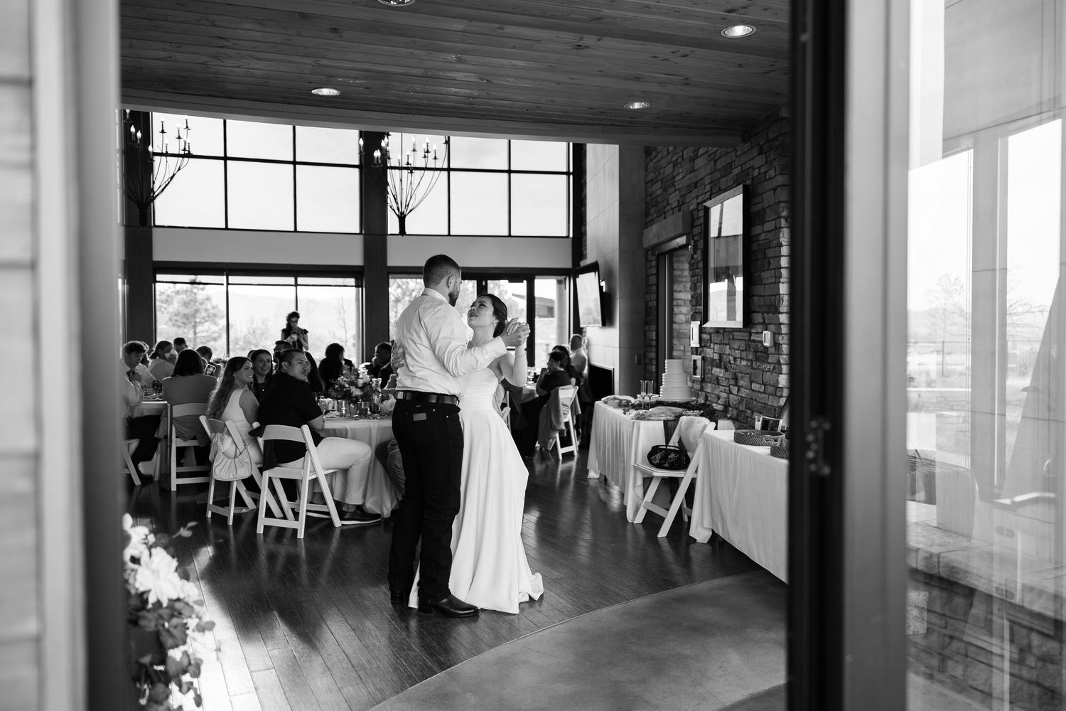 Bride and groom share their first dance in an elegant rustic reception venue in black and white.