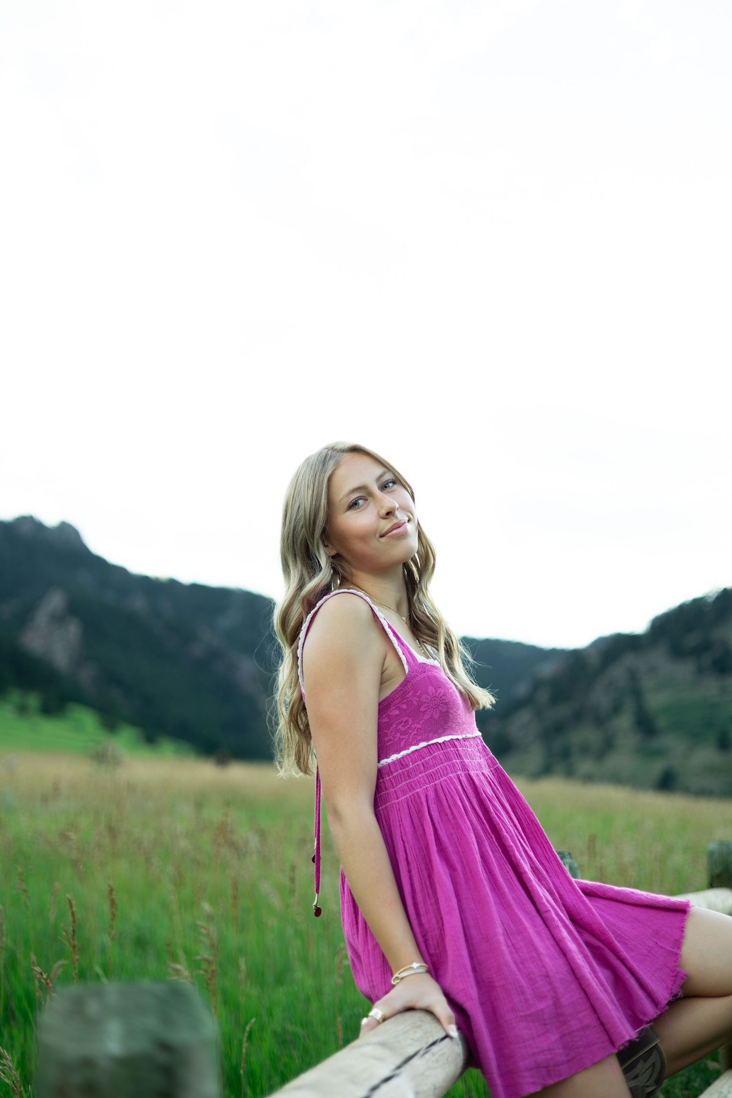 A sequence of playful poses captured in a bright pink dress against a mountainous landscape.