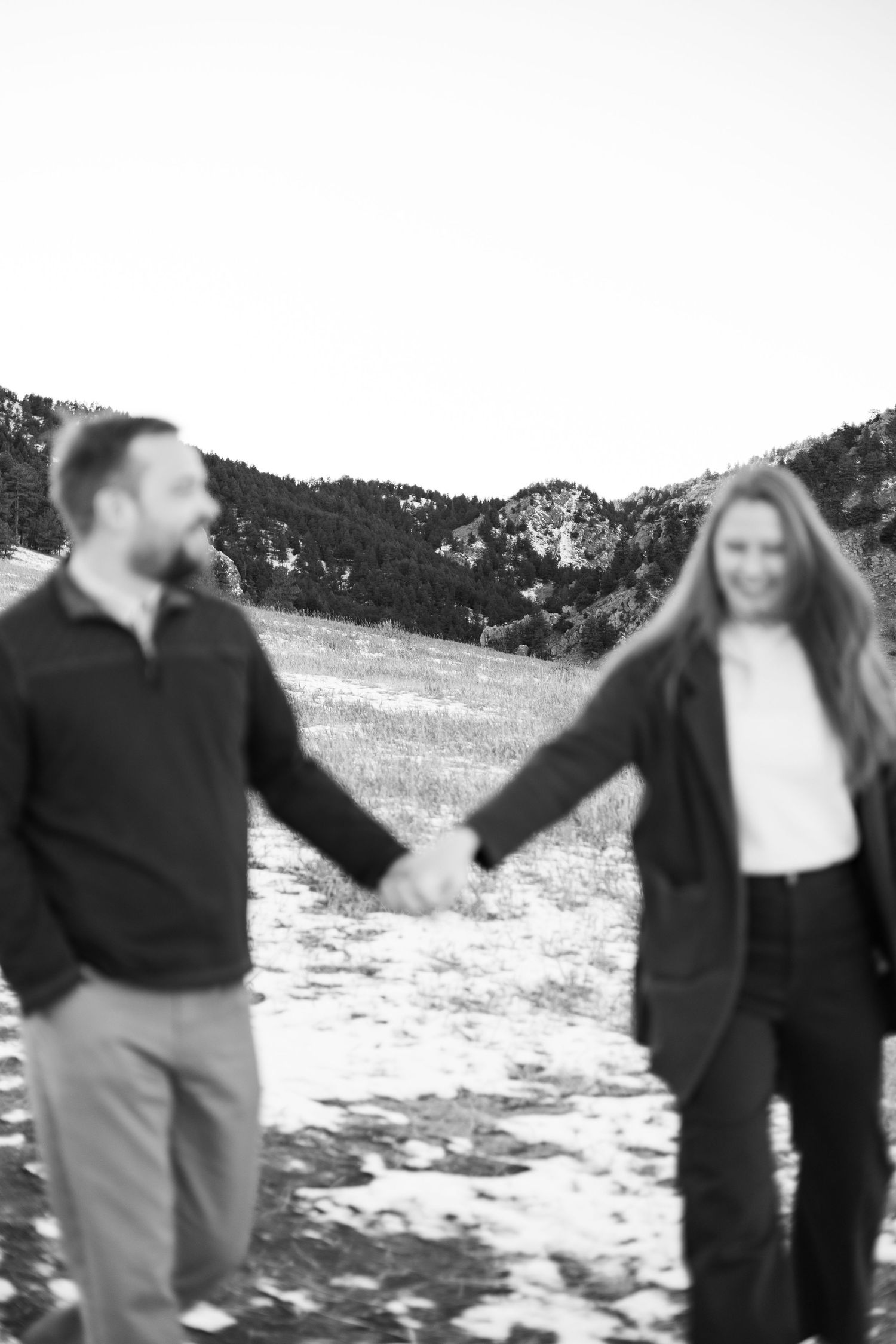 Couple holding hands in a snowy mountain landscape with a soft focus effect.