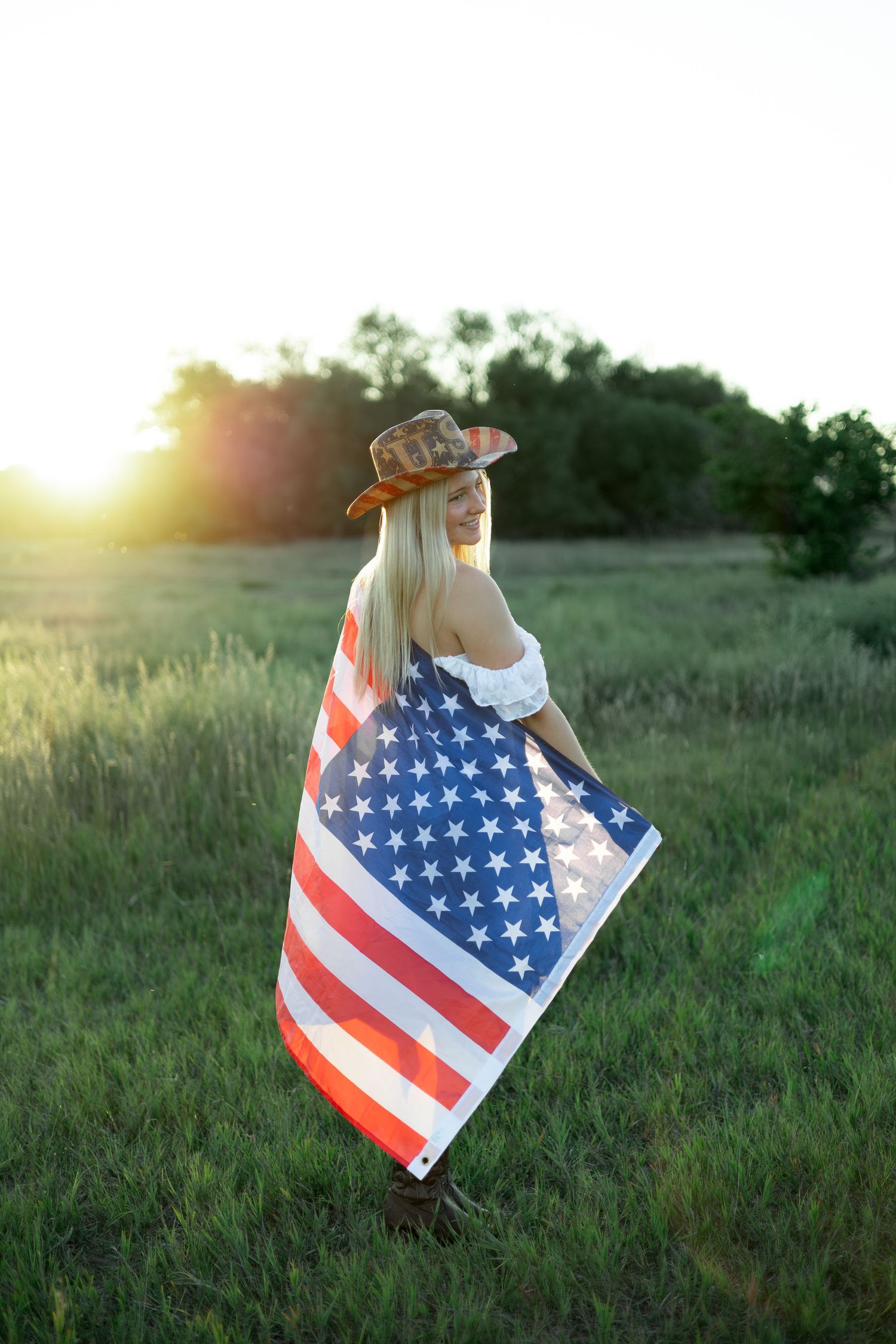 American flag waves gracefully in a sunlit meadow during golden hour.