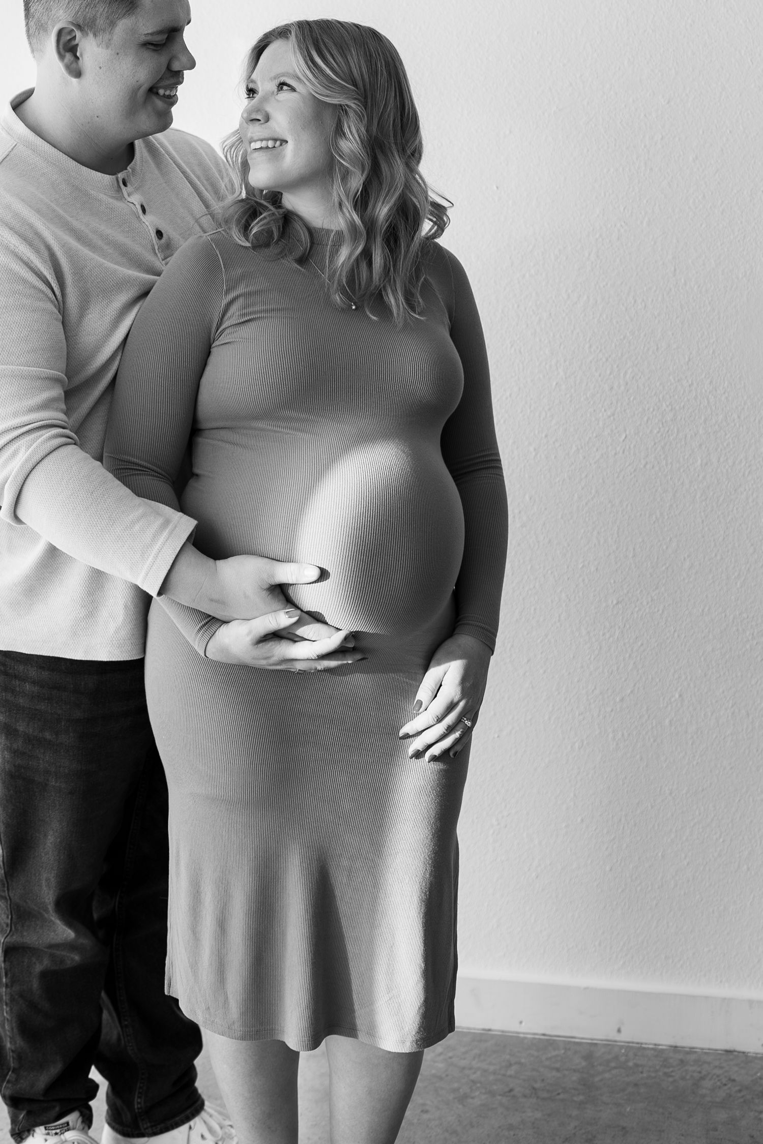 A couple embraces tenderly while expecting a baby, shown in a series of intimate black and white maternity photos.