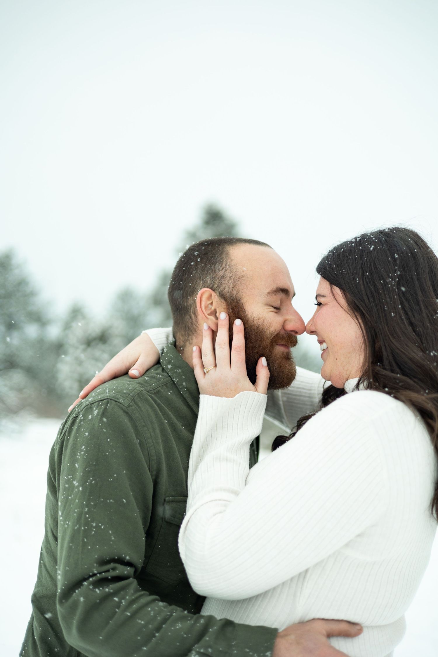 Intimate winter portrait of couple laughing in the falling snow.