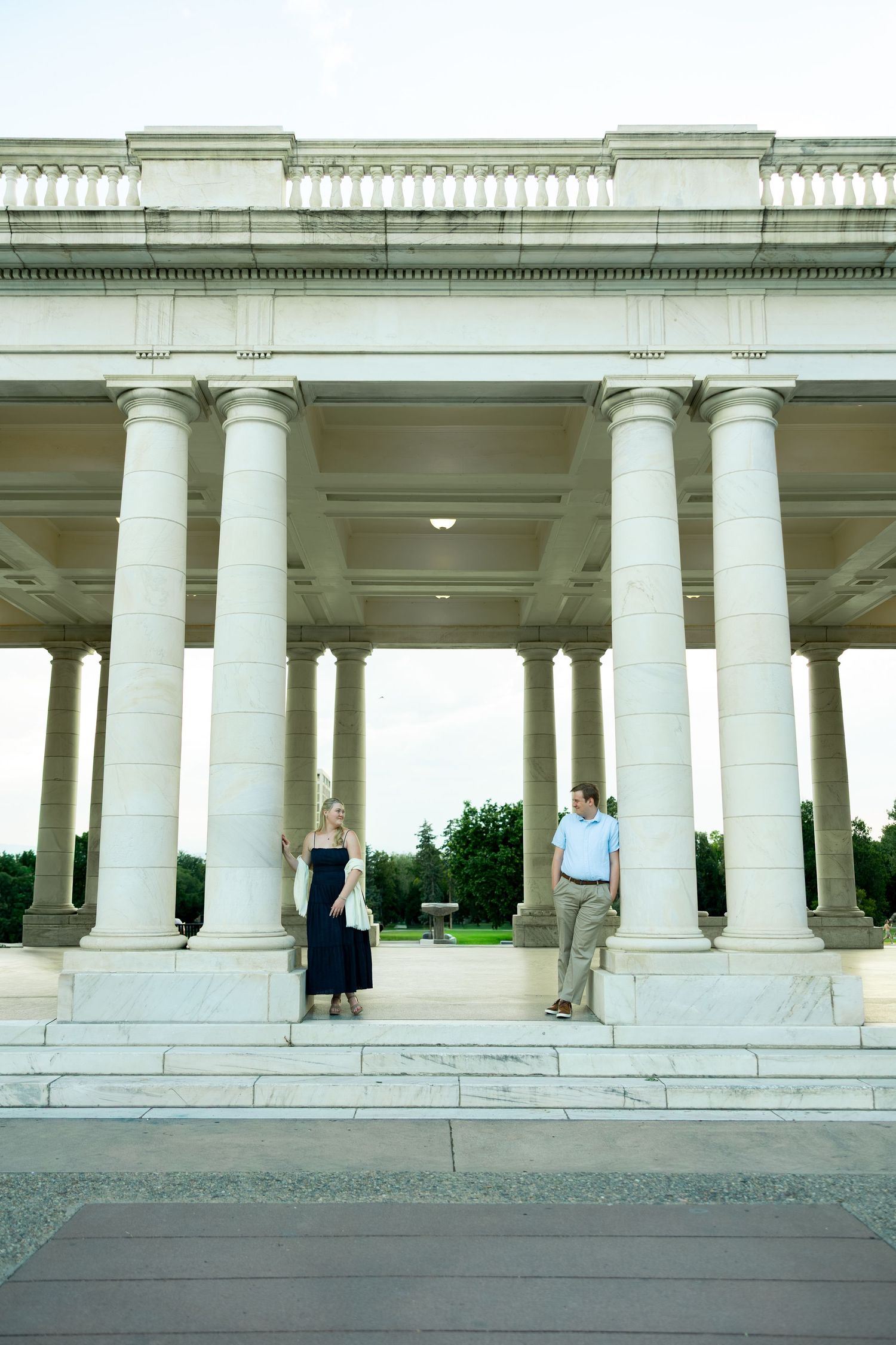 Couple standing on marble steps of a grand neoclassical building with tall white columns.