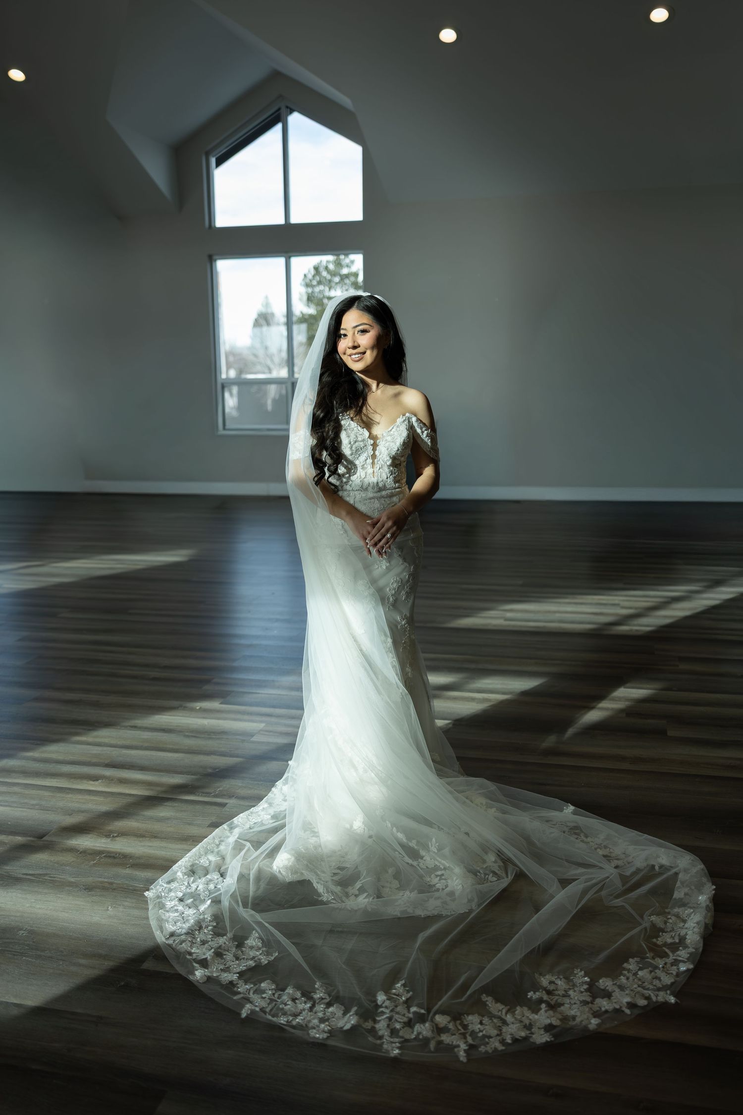 A wedding dress with intricate lace detail photographed in dramatic lighting.