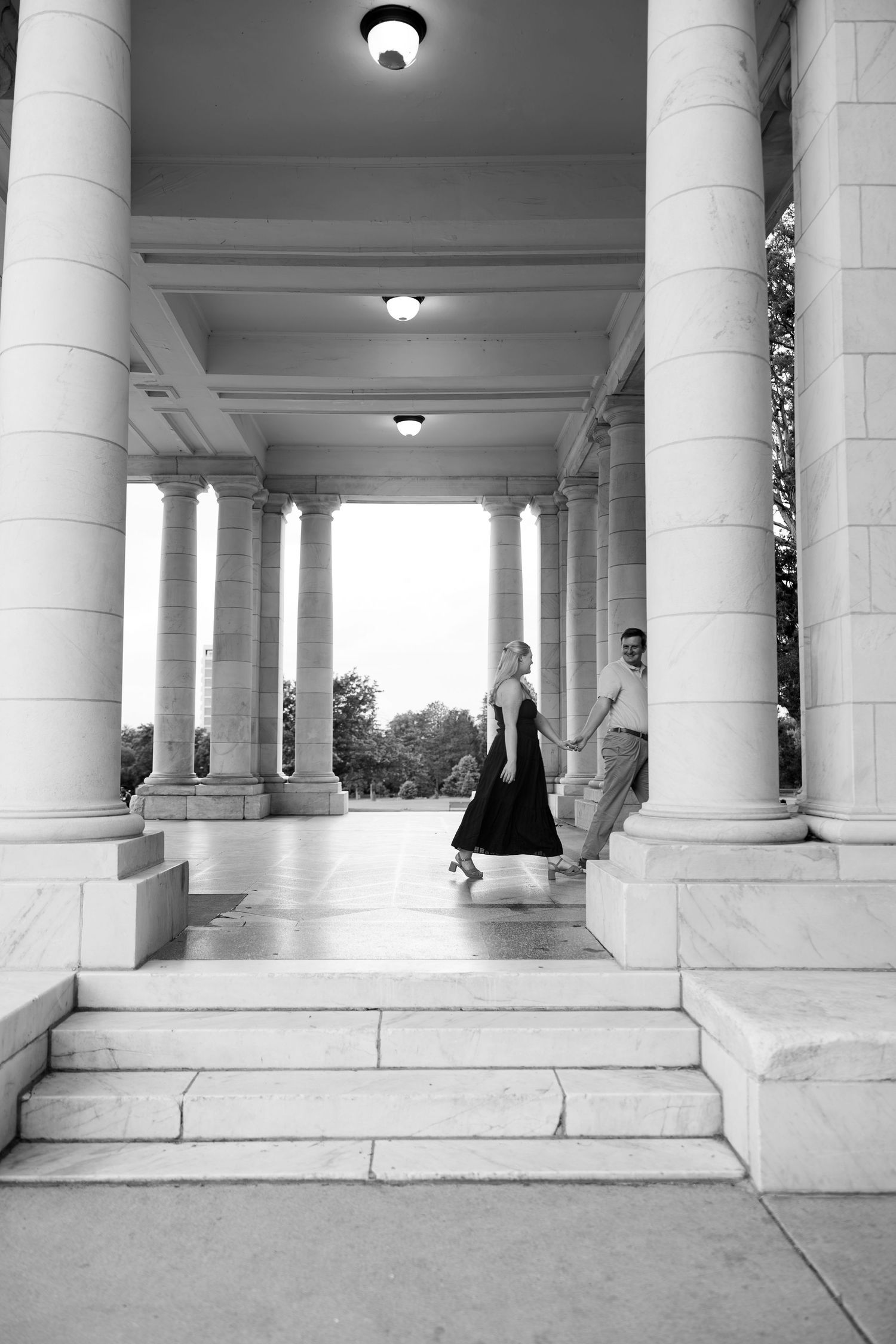Black and white photo of a couple walking through elegant marble columns on grand steps of a neoclassical building.