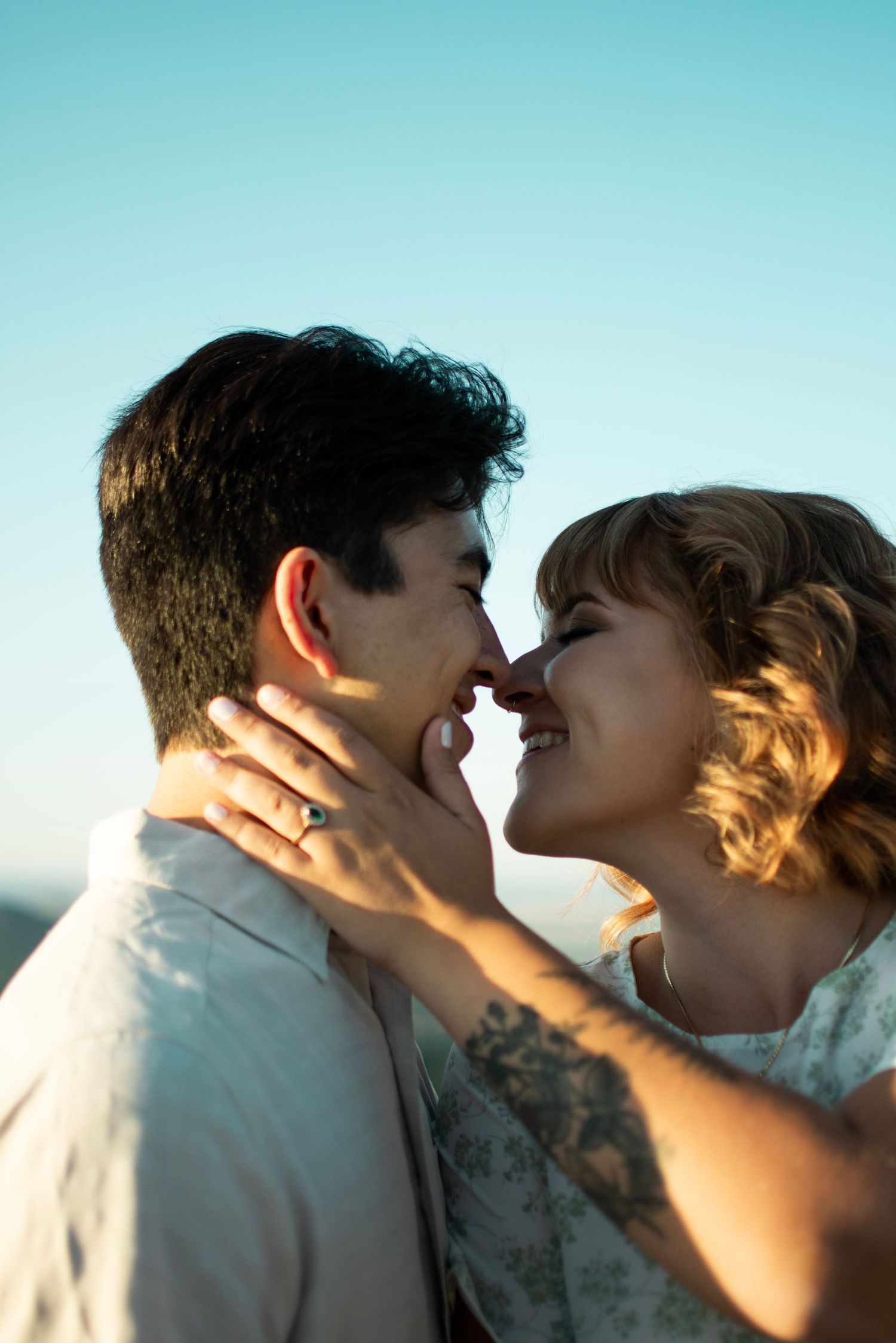 A tender moment between a couple during golden hour with a ring visible.
