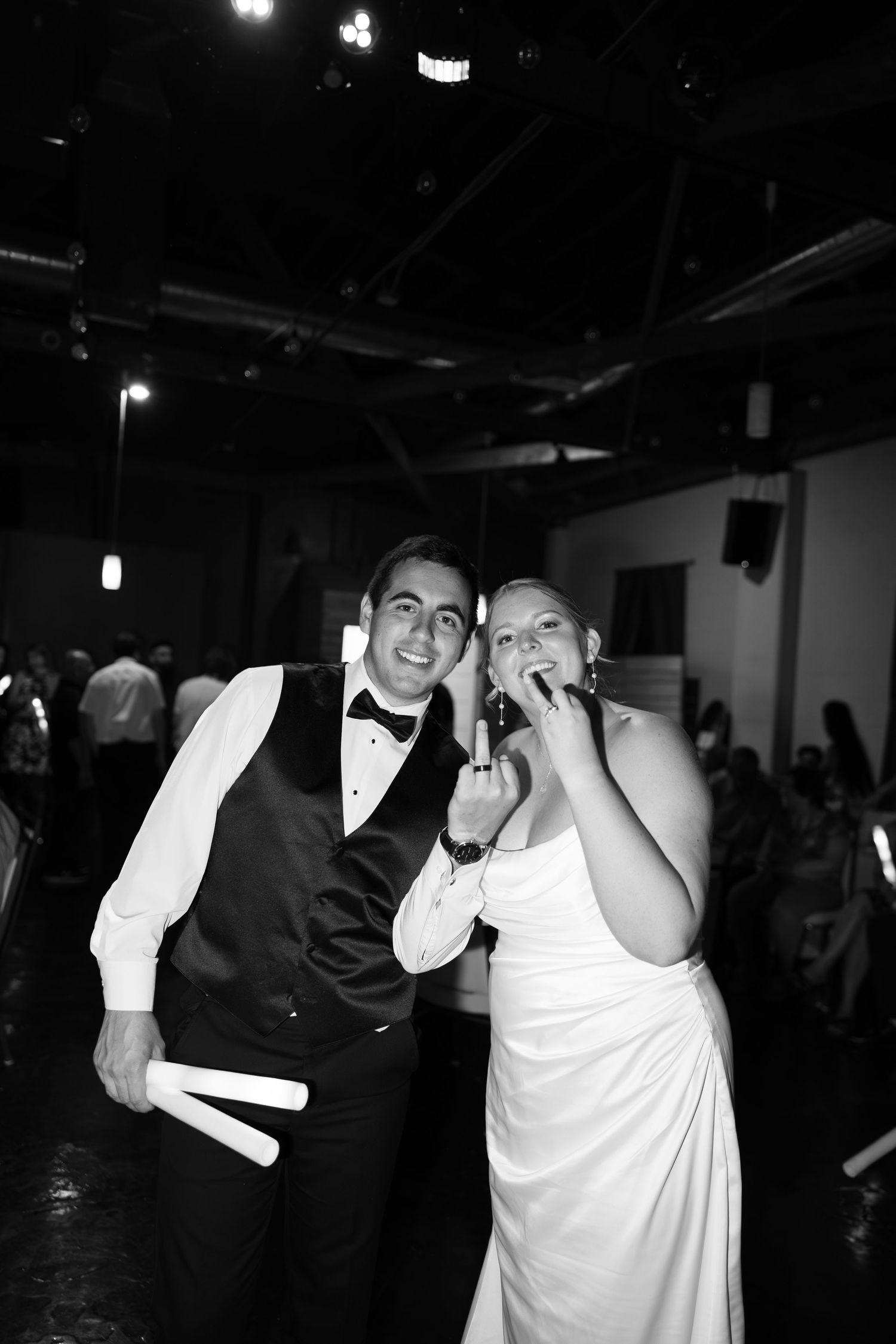 Black and white photo of a smiling bride and groom celebrating at their wedding reception venue.