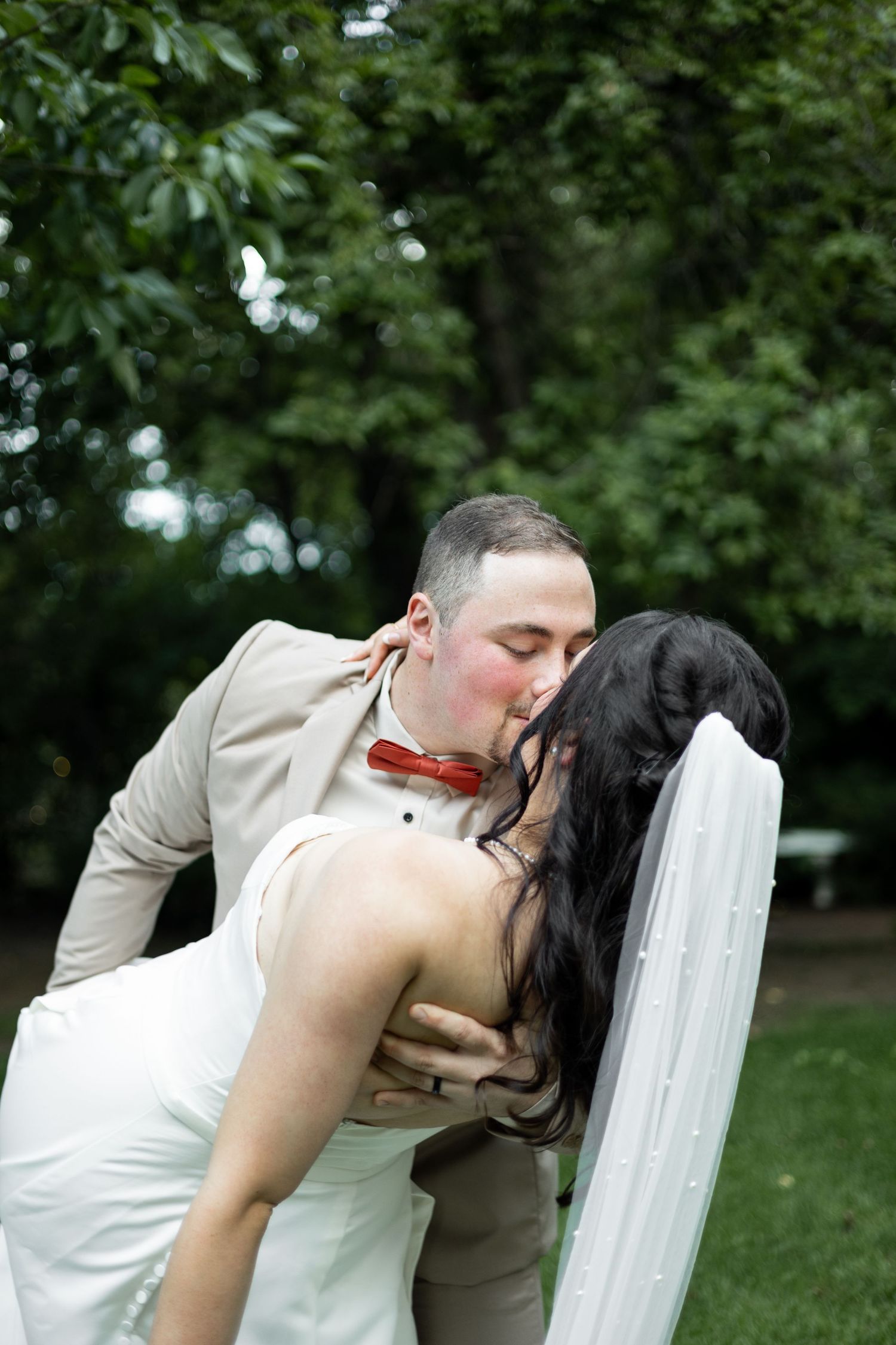 Romantic dip kiss pose captured during an outdoor wedding photoshoot.