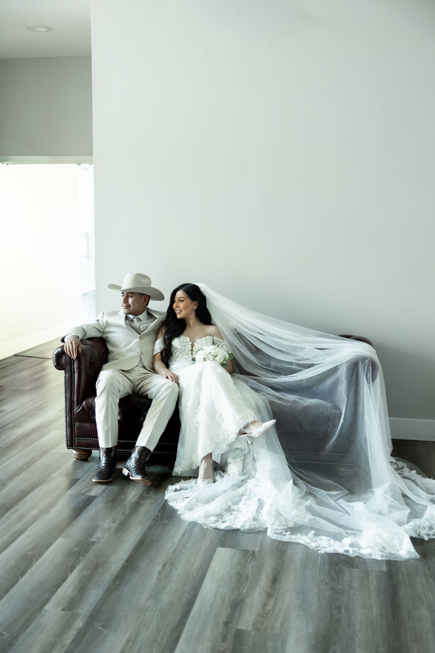 An artistic wedding photo series showing a couple posing on grey flooring with a flowing veil.