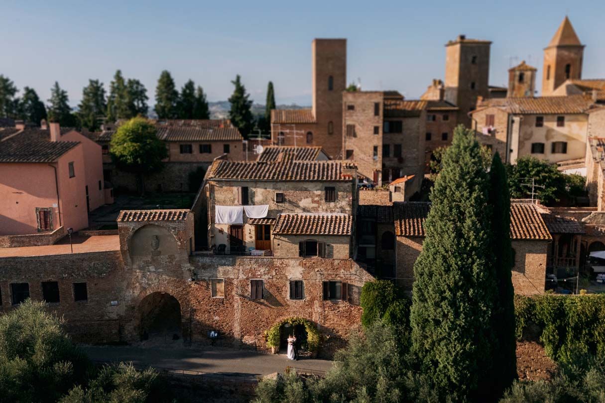 Medieval castle towers and stone buildings rise above the treetops in San Gimignano, Tuscany, Italy.