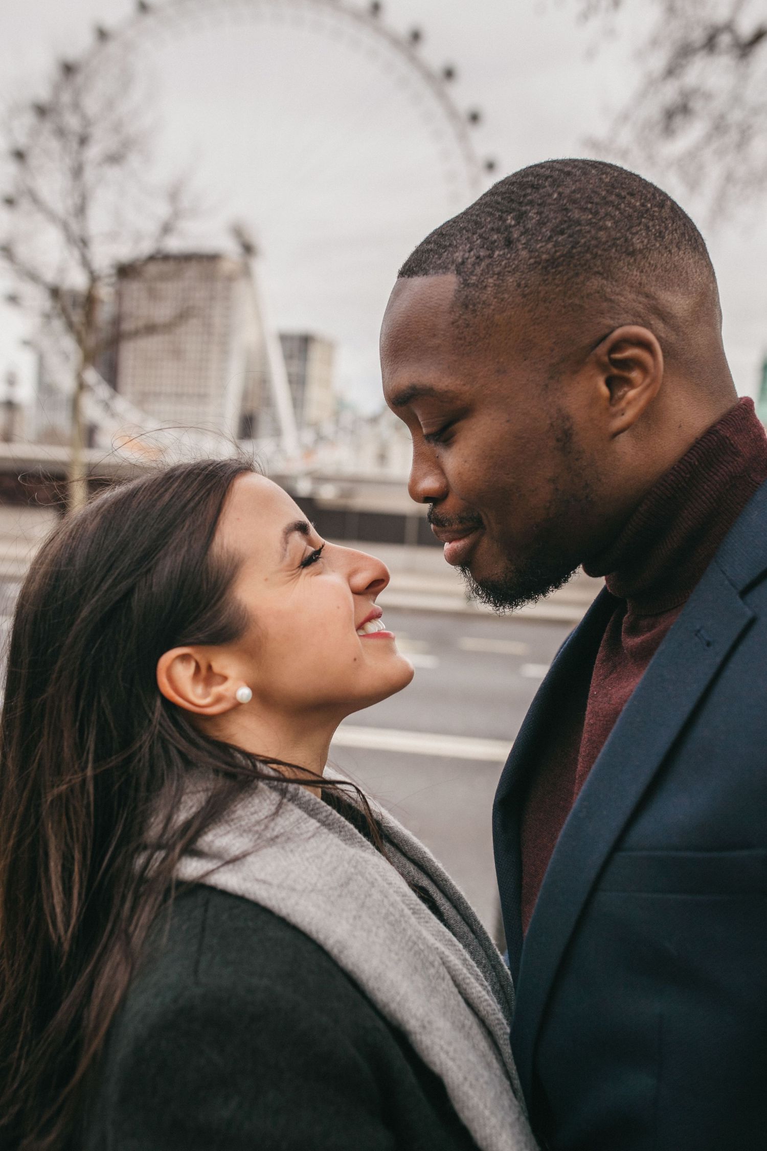 Romantic couple share an intimate moment near the London Eye on a moody winter day.