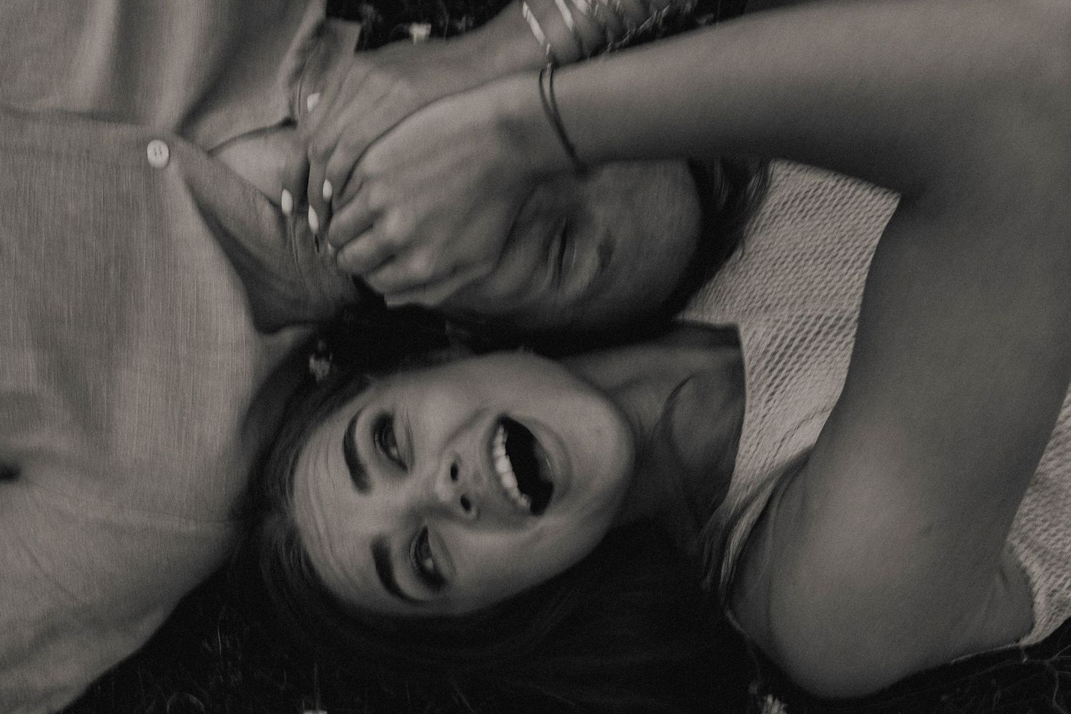 A black and white close-up photograph shows a carefree moment with hands raised and joyful expression.