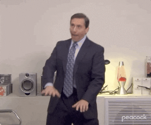 Business professionals gesture and discuss in an office setting during a presentation or meeting.