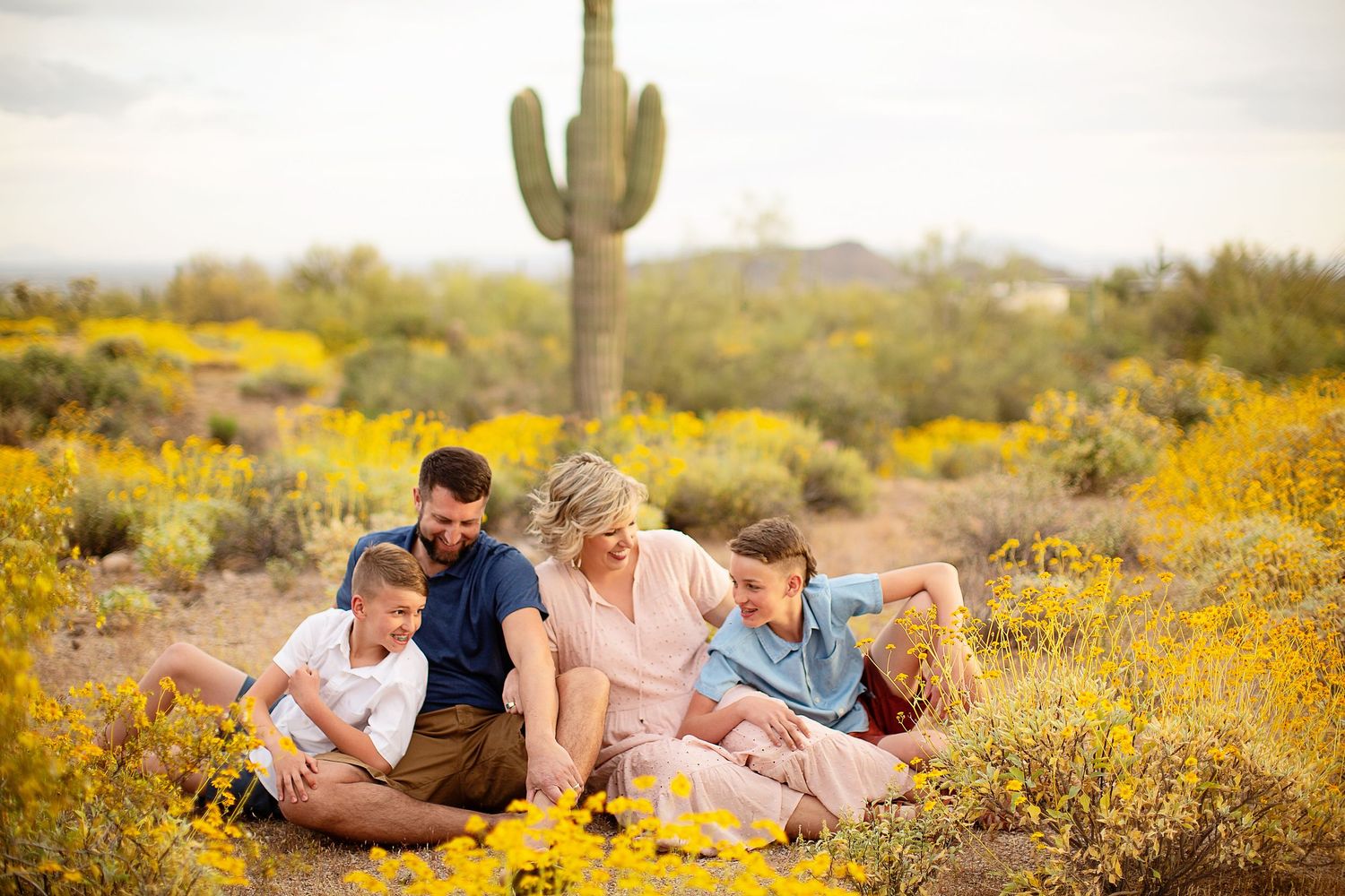 People lounging together in a desert field with yellow wildflowers blooming at sunset.