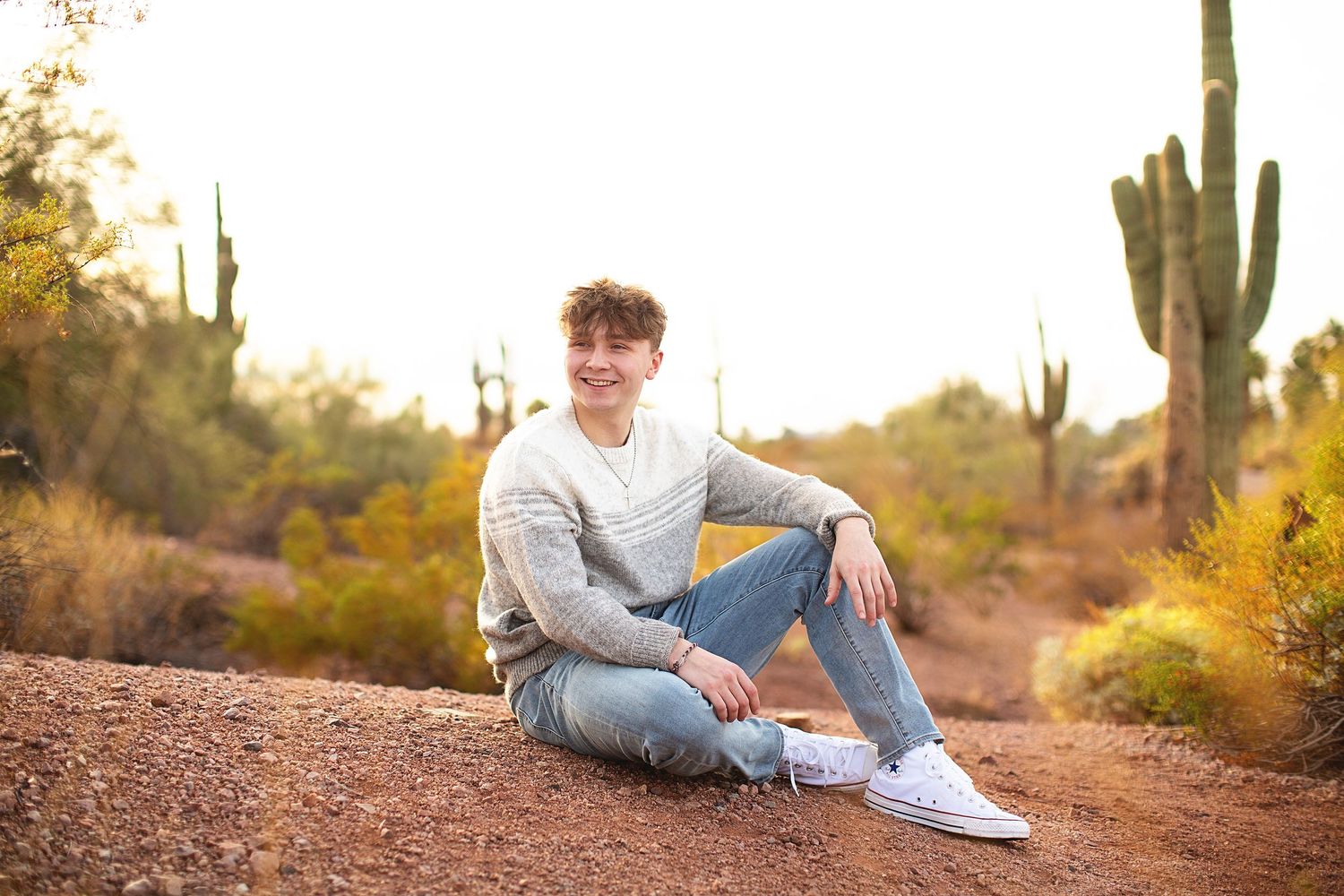Senior photo session in desert landscape with saguaro cacti at sunset.