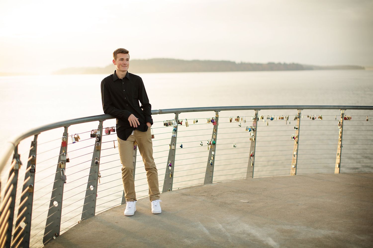 People walking along waterfront railing at sunset.