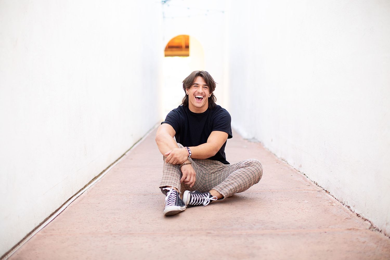 Minimalist portrait series against white wall showing casual sitting poses.